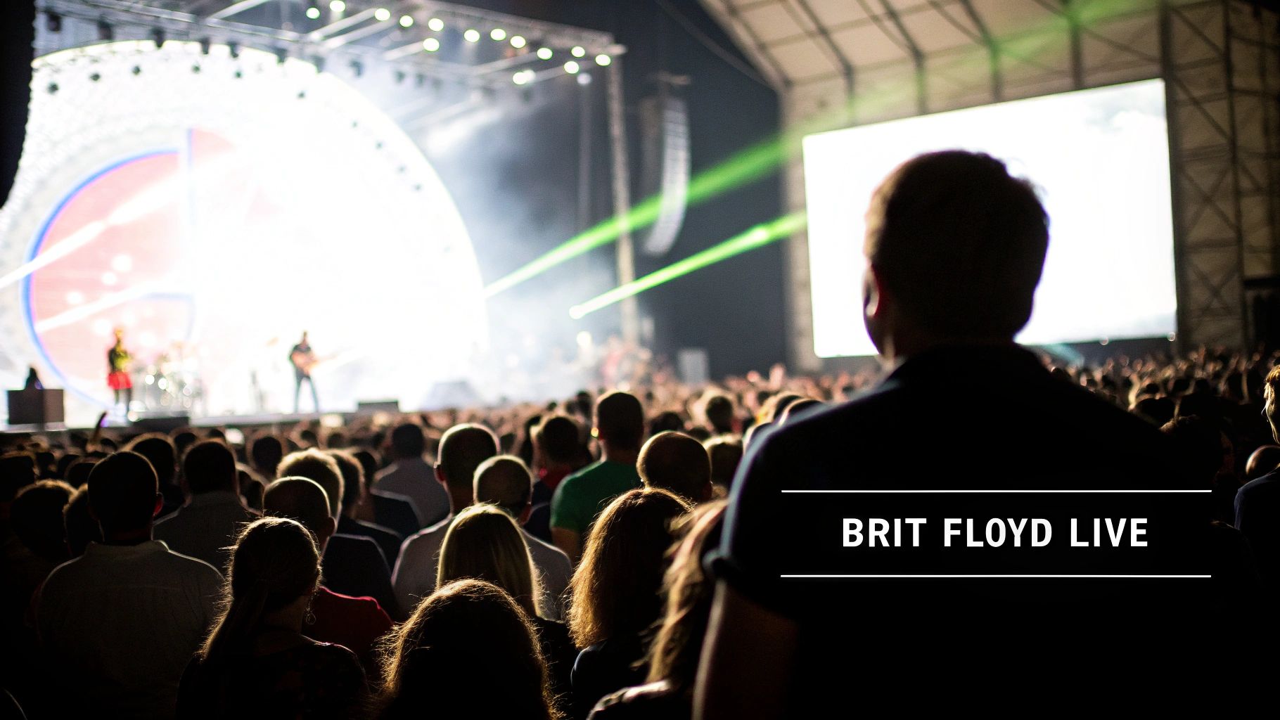 Concertgoers enjoying a Brit Floyd live performance on a brightly lit stage with laser lights and a large screen.