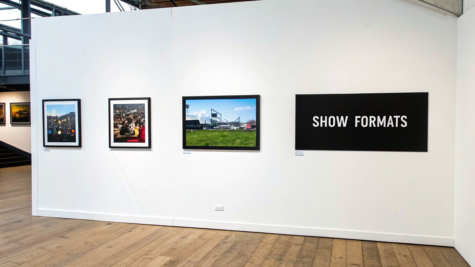 An art exhibition wall displays several framed photographs and a black 'SHOW FORMATS' sign.