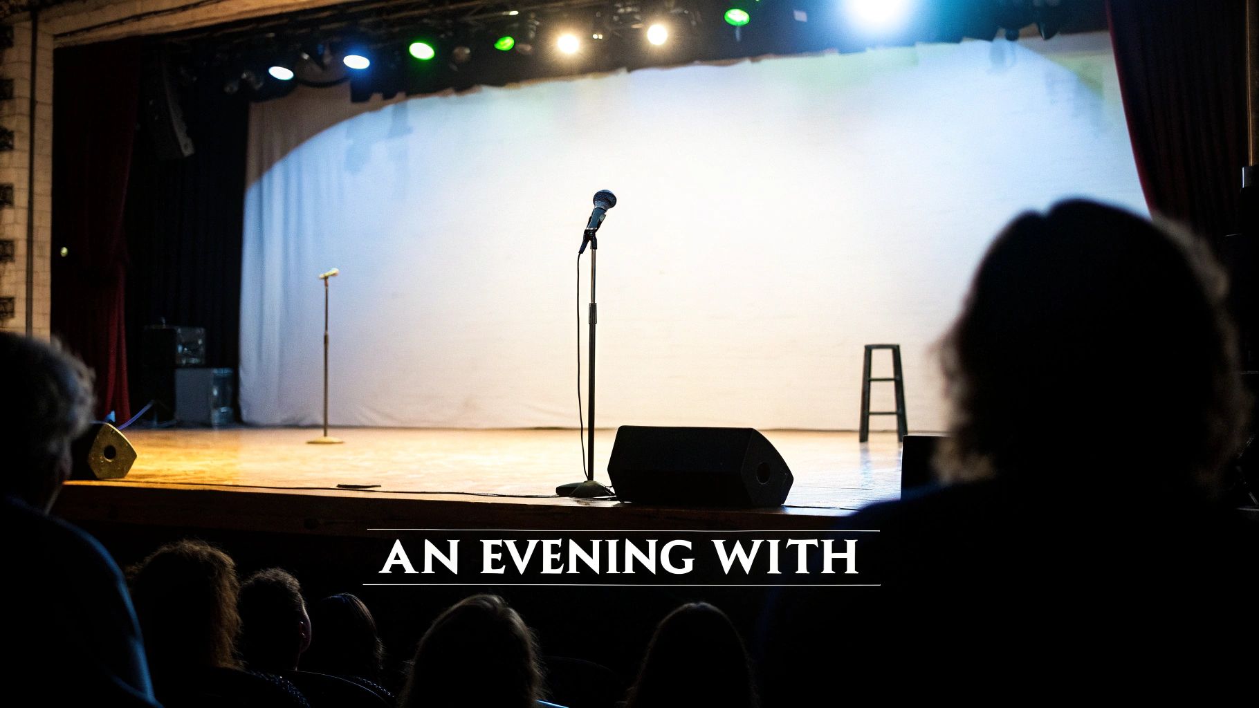 An empty stage with two microphones, a speaker, and a stool, viewed from an audience perspective. The text 'AN EVENING WITH' is overlayed.