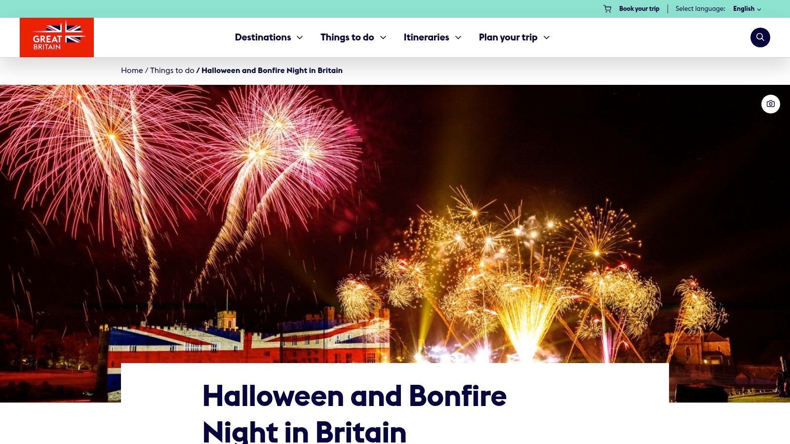 A large castle illuminated at night with a spectacular fireworks display in the sky above, reflecting in the water below.