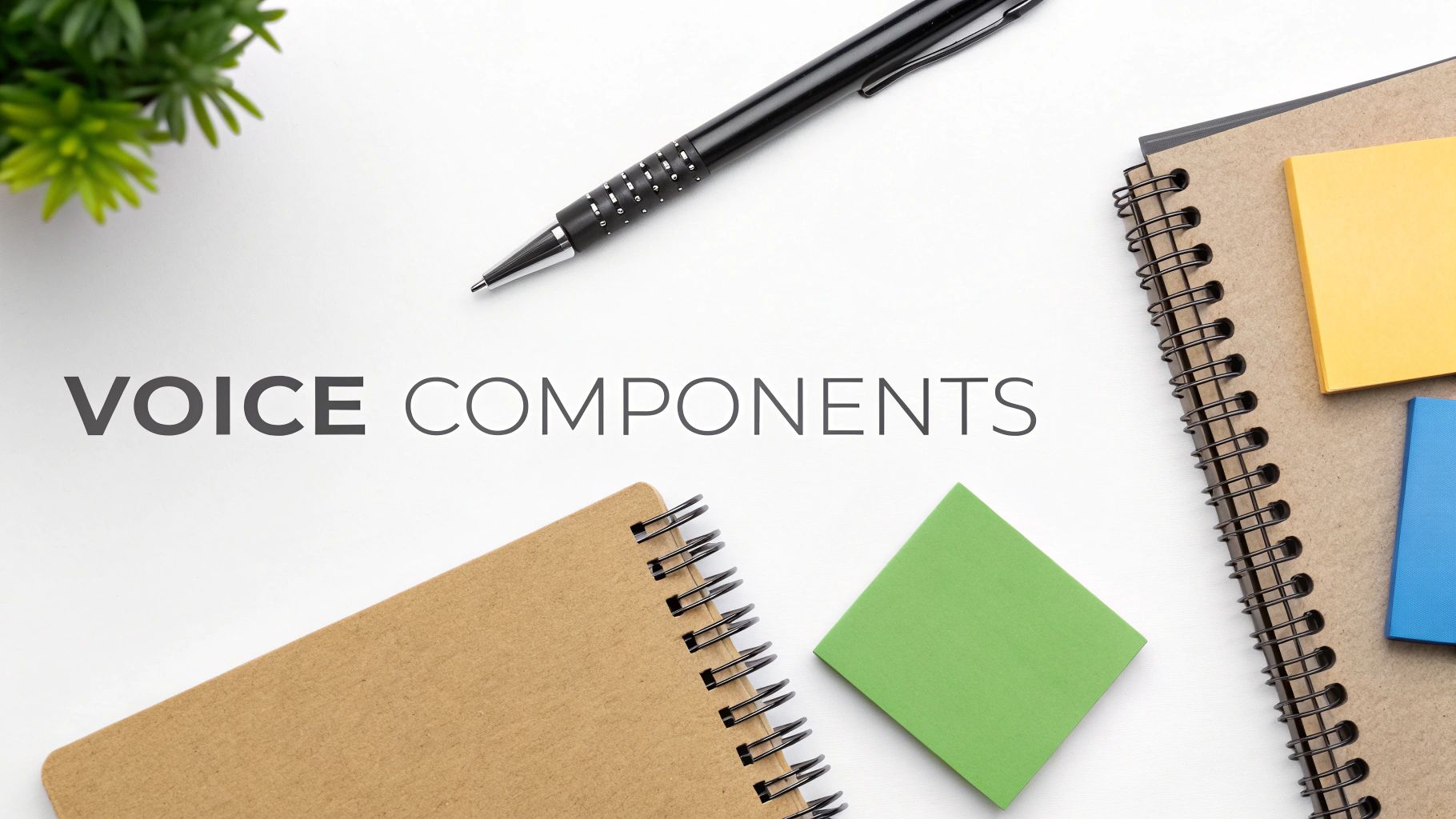 Overhead shot of a white desk with 'VOICE COMPONENTS' text, a pen, notebooks, and sticky notes.