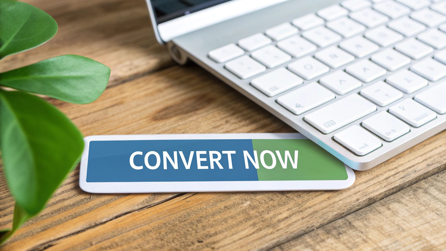 A 'CONVERT NOW' call-to-action sign on a wooden desk with a laptop and plant.