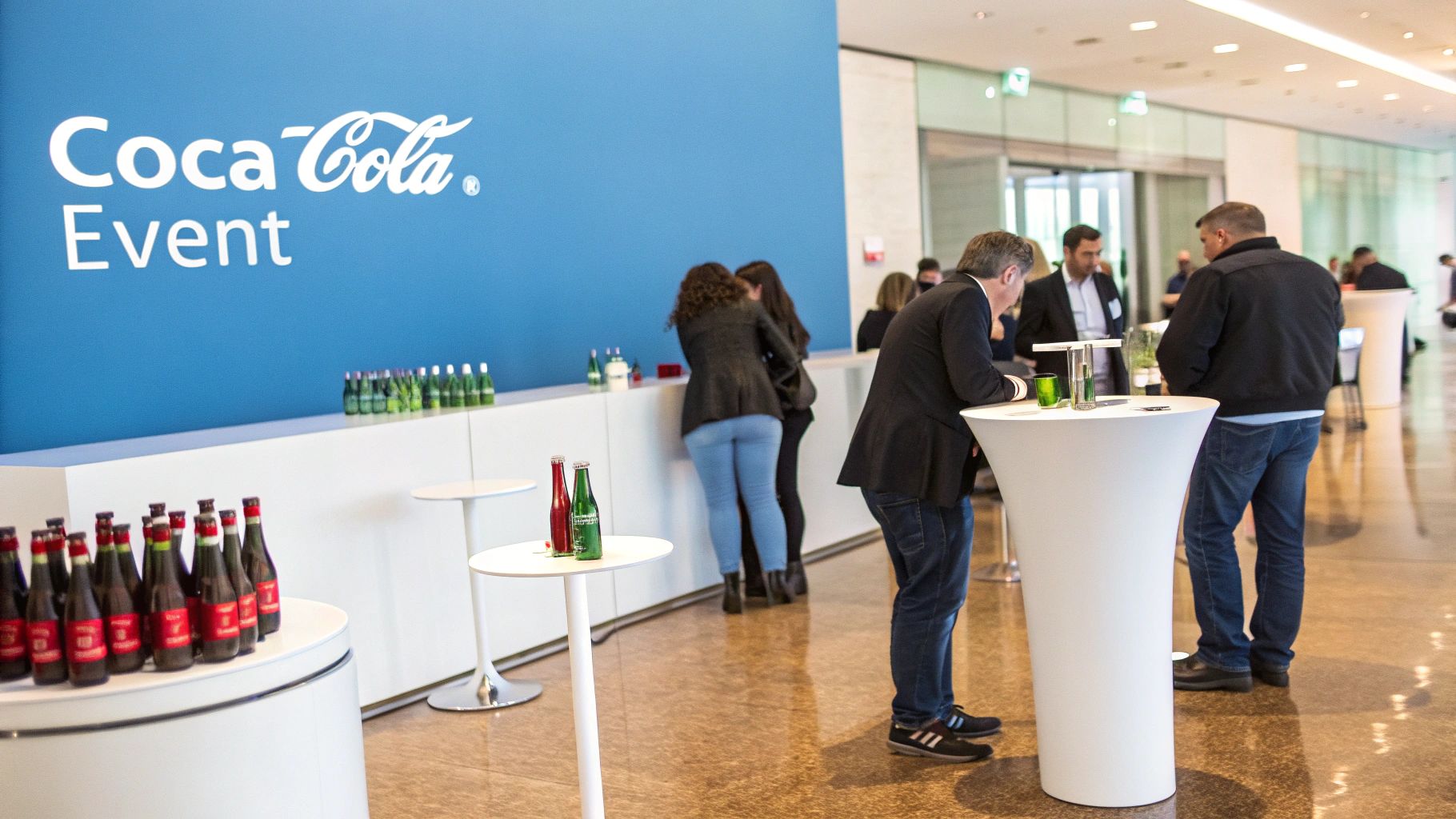 Attendees socialize and enjoy beverages at a modern Coca-Cola event with branded displays.