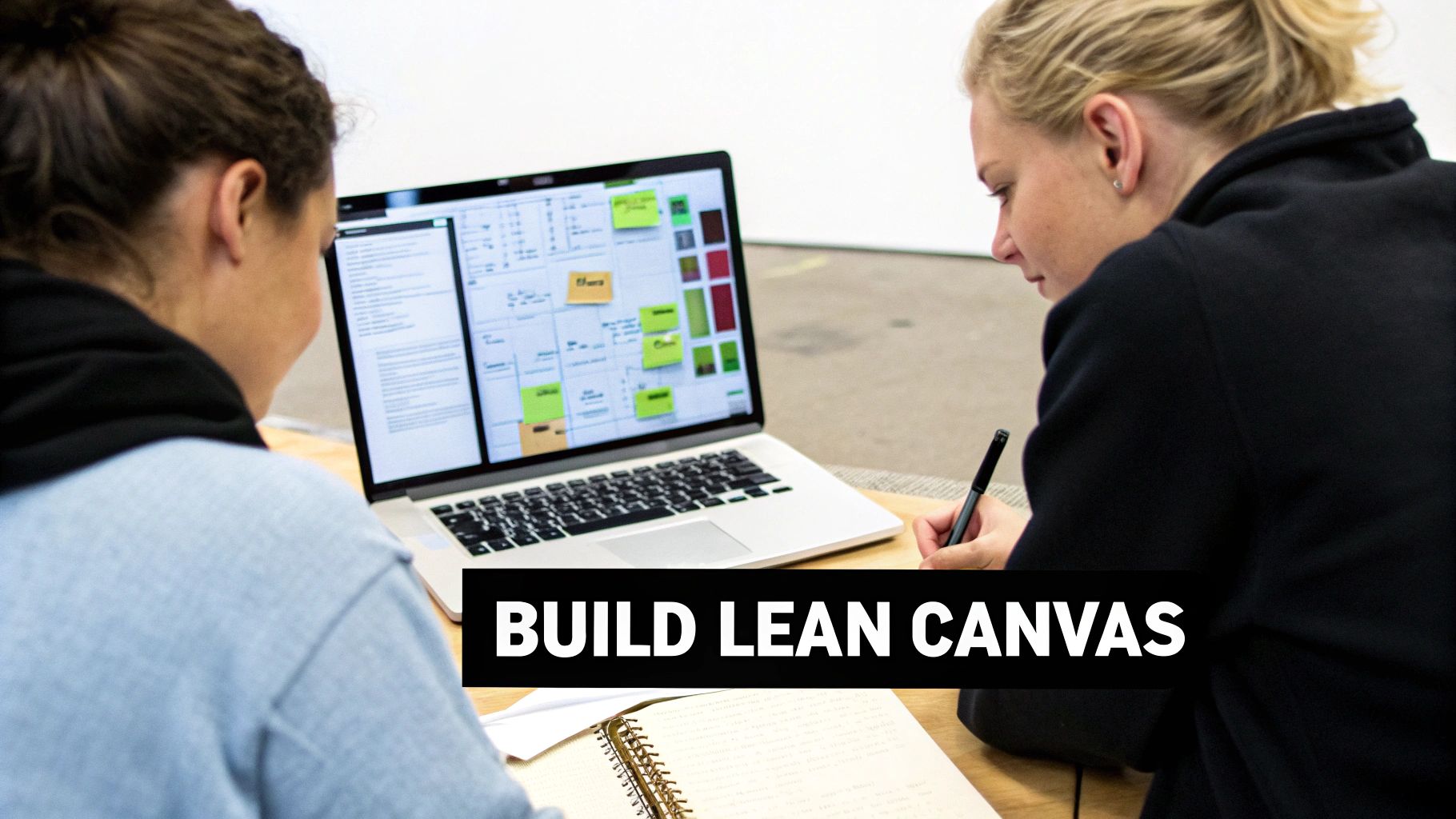 Two individuals collaborate on a laptop displaying a lean canvas, while one takes notes.