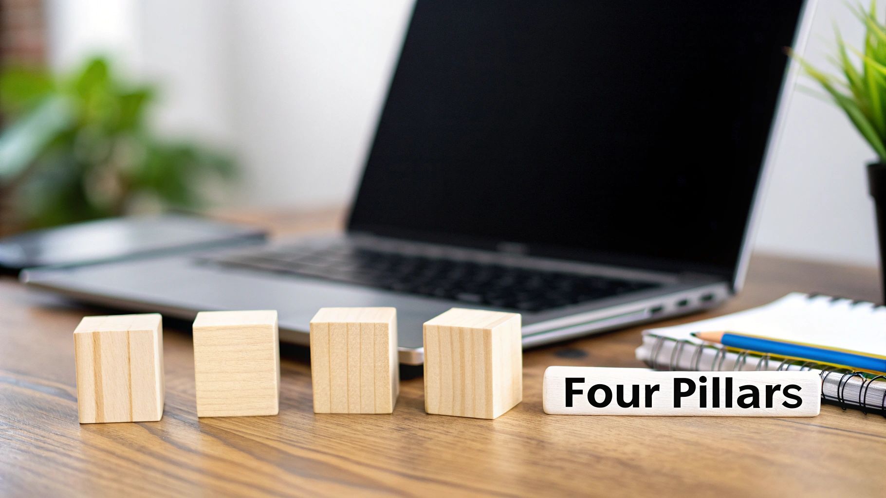 Four wooden blocks and a 'Four Pillars' sign on a wooden desk with a laptop and notebook.