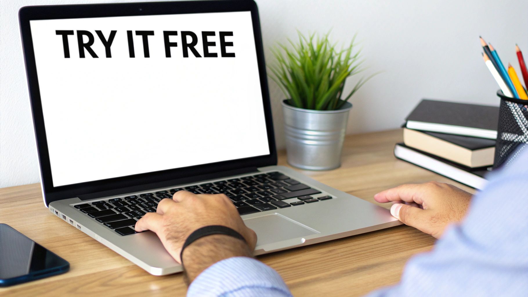 A person uses a laptop displaying 'TRY IT FREE' on a wooden desk with a plant, books, and pencils.