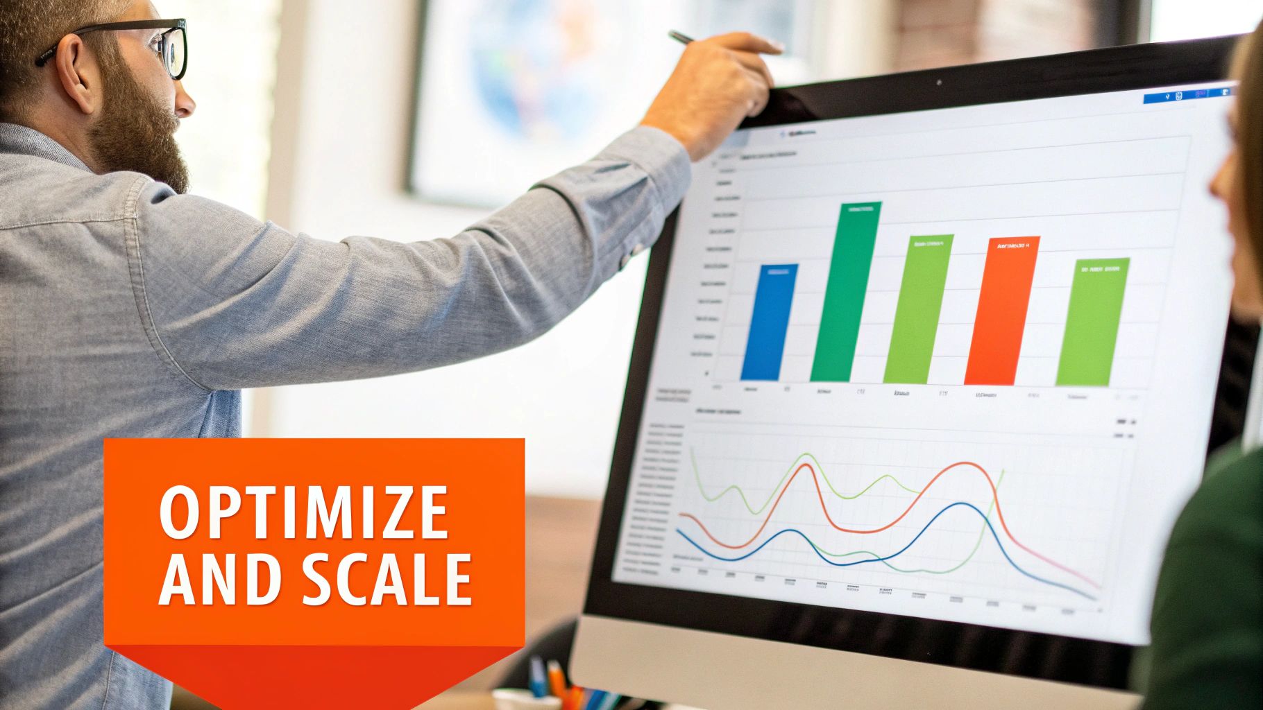 A man points at a computer screen displaying colorful business growth charts and data visualization.
