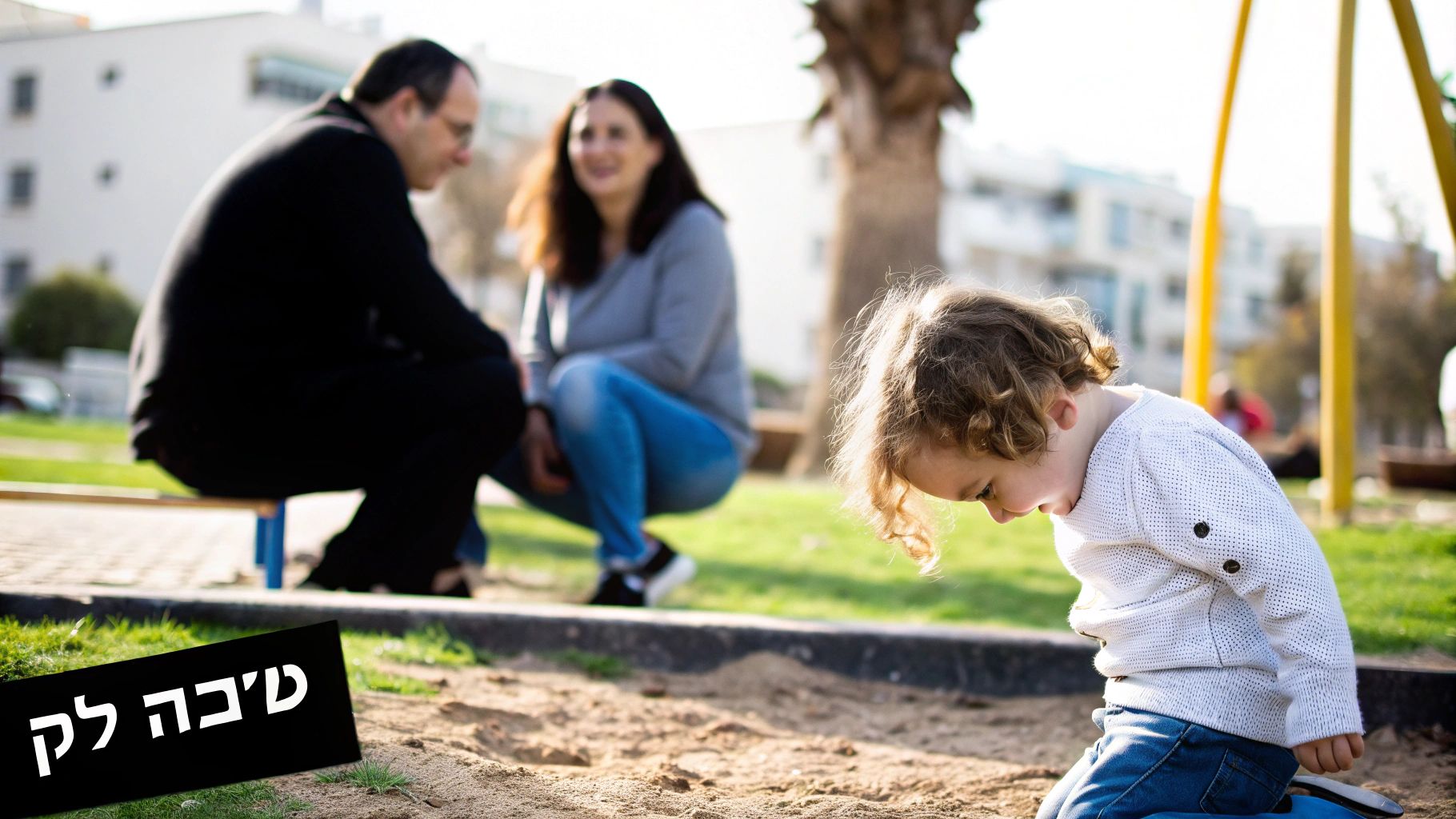 ילד קטן משחק בארגז חול בפארק, הורים יושבים ברקע, סצנה משפחתית באור יום.