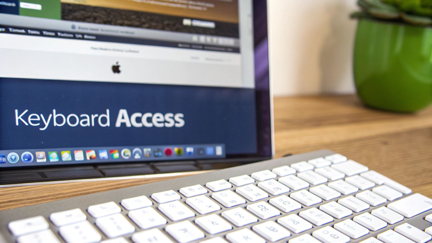 A laptop screen displays "Keyboard Access" with an Apple keyboard in the foreground on a wooden desk.