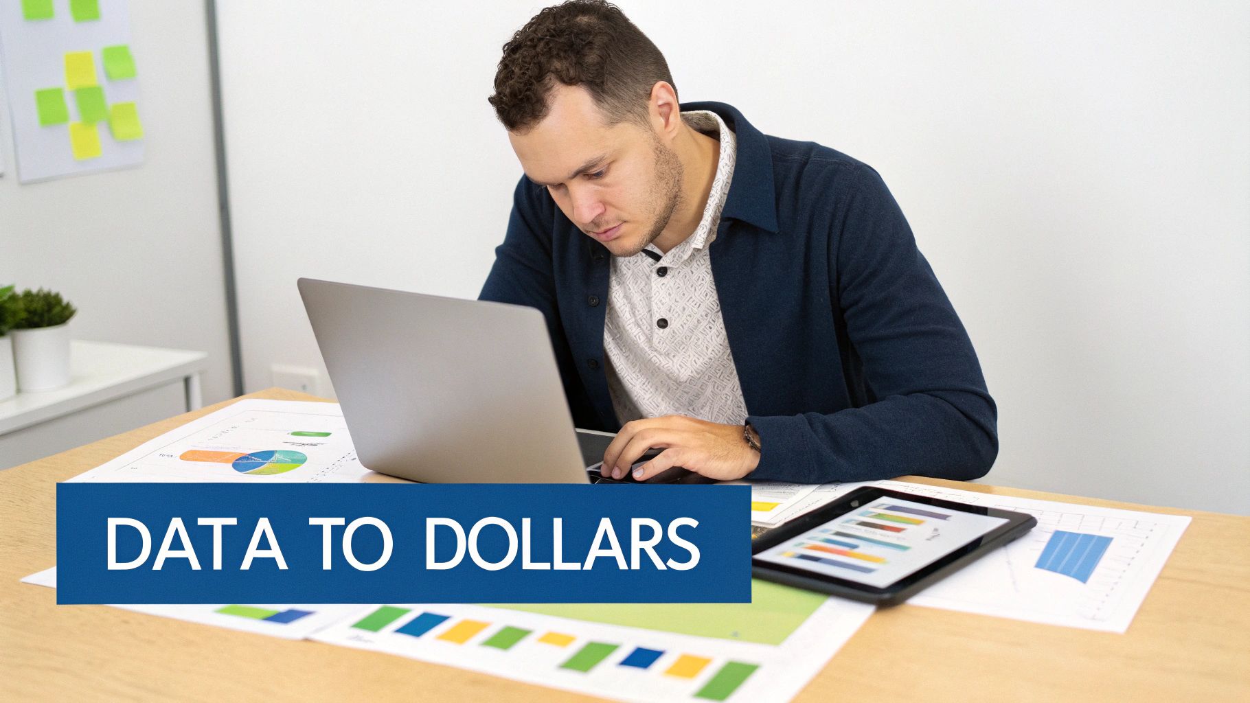 A man works on a laptop at a desk with charts, graphs, and a tablet, symbolizing data analysis.