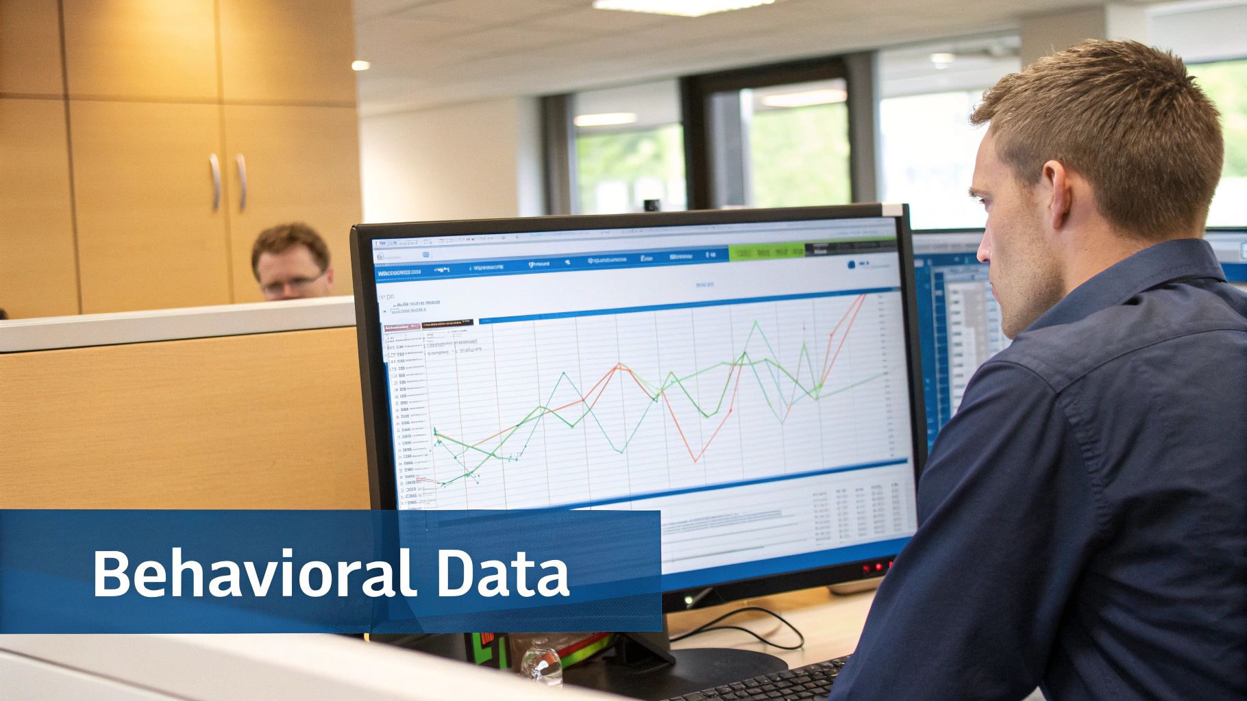 A man analyzing behavioral data on multiple computer screens in a modern office environment.