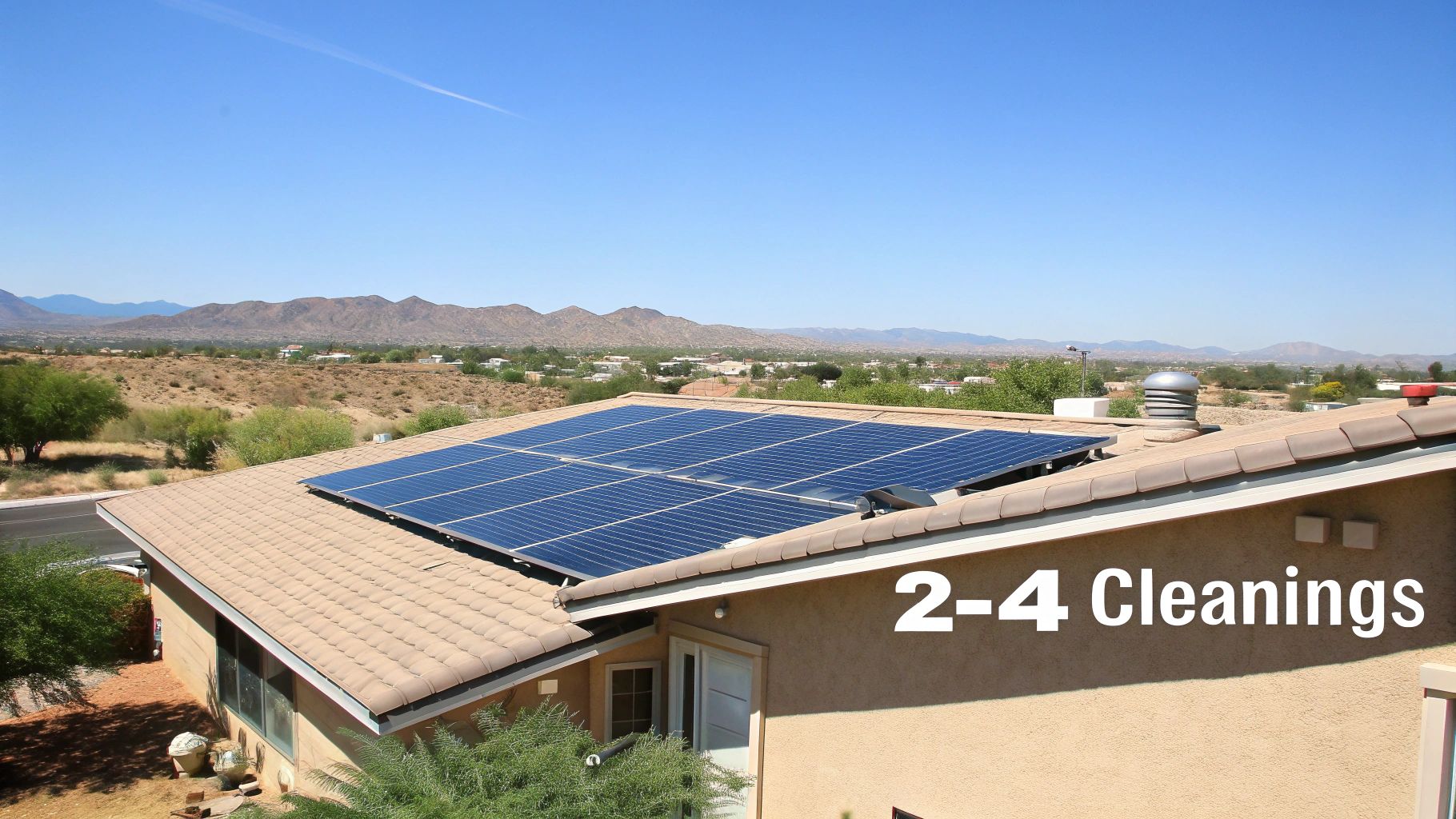 A house with blue solar panels on a tiled roof, set against a desert landscape and mountains.