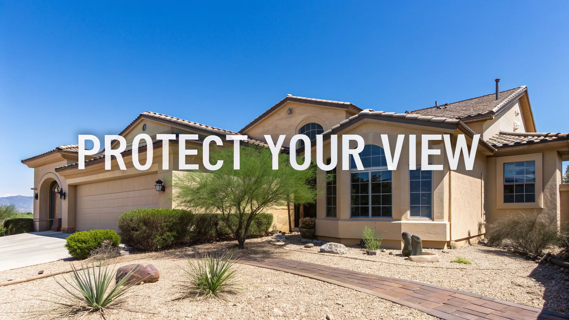 A large, modern stucco house with desert landscaping under a clear blue sky.