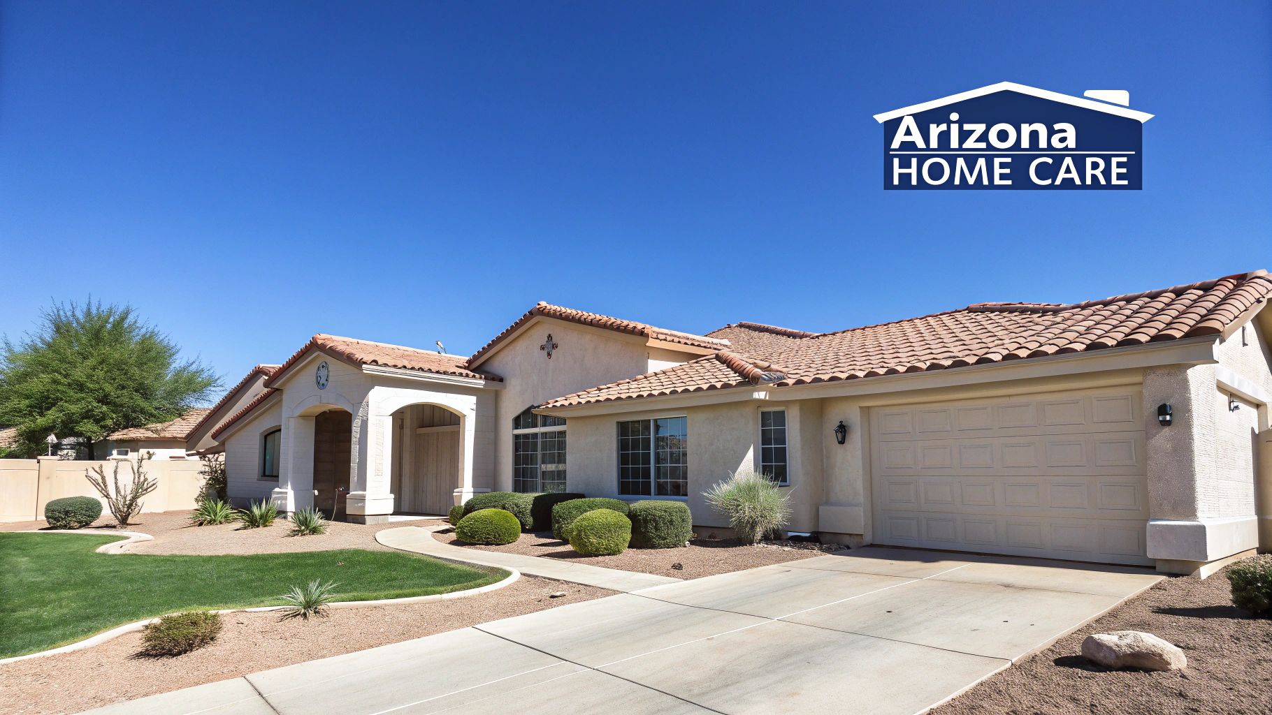 A cream-colored house with a red tile roof, large driveway, green lawn, and desert landscaping.