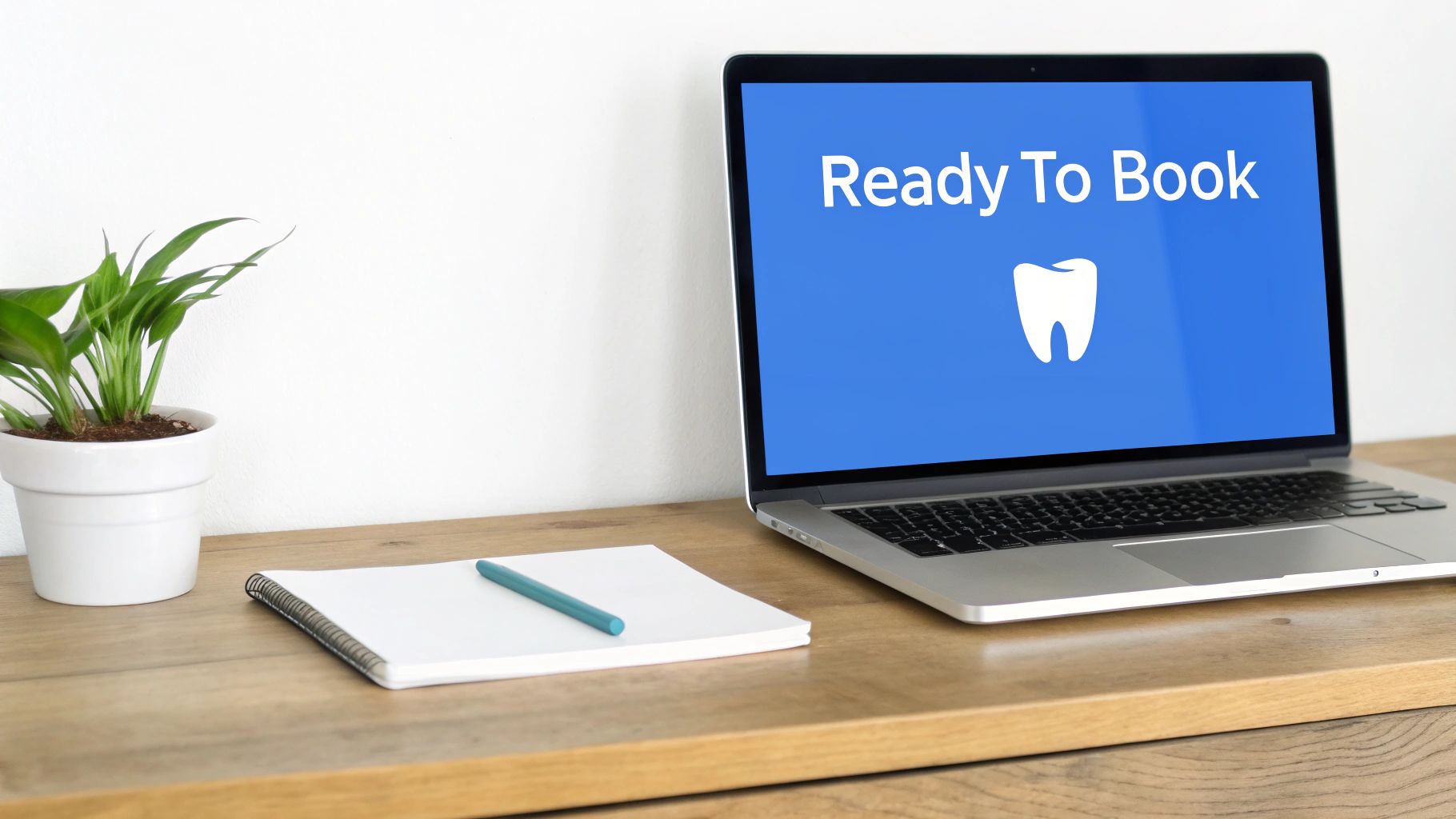 A laptop on a wooden desk displays 'Ready To Book' with a white tooth icon, alongside a plant.
