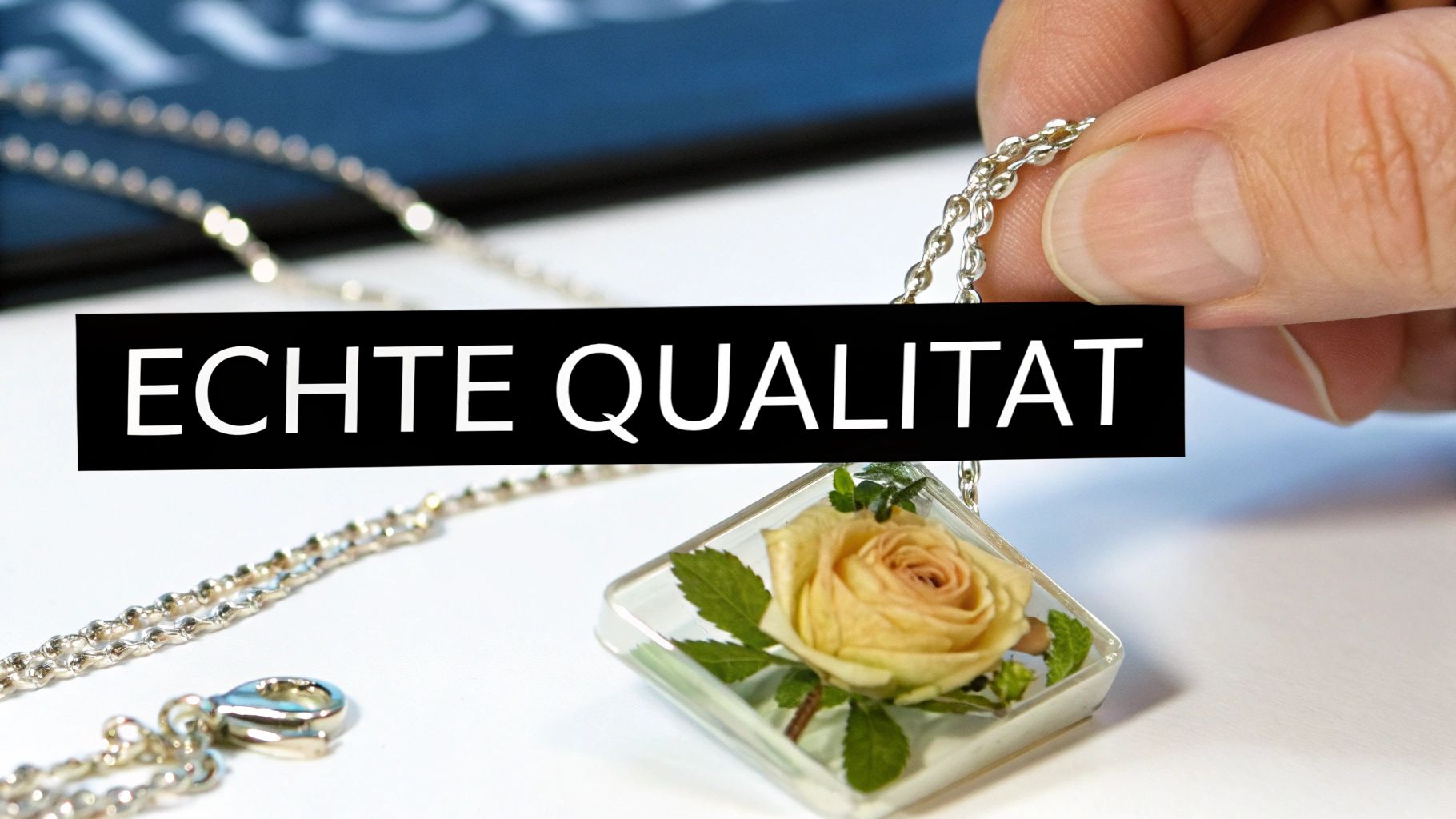 Una mano sostiene una cadena de plata con un colgante cuadrado que contiene una rosa amarilla preservada. La inscripción dice: «Calidad Genuina».