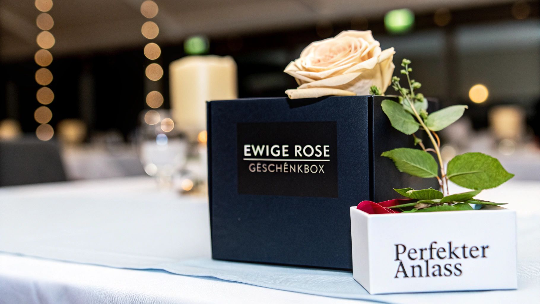 Elegante dunkelblaue Geschenkbox mit ewiger Rose und Schriftzug 'Perfekter Anlass' auf einem festlich gedeckten Tisch.