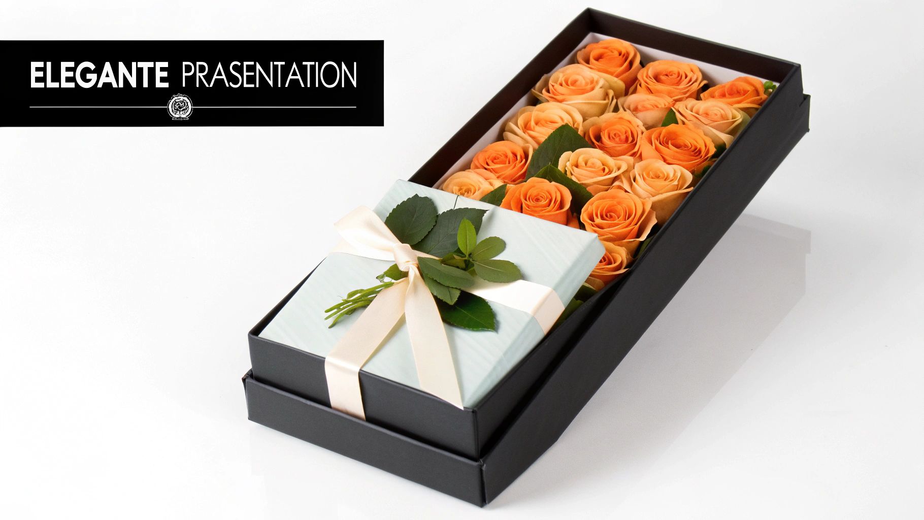 Eine offene schwarze Box mit orangen Rosen und einem hellblauen Geschenk mit Schleife und Blättern.