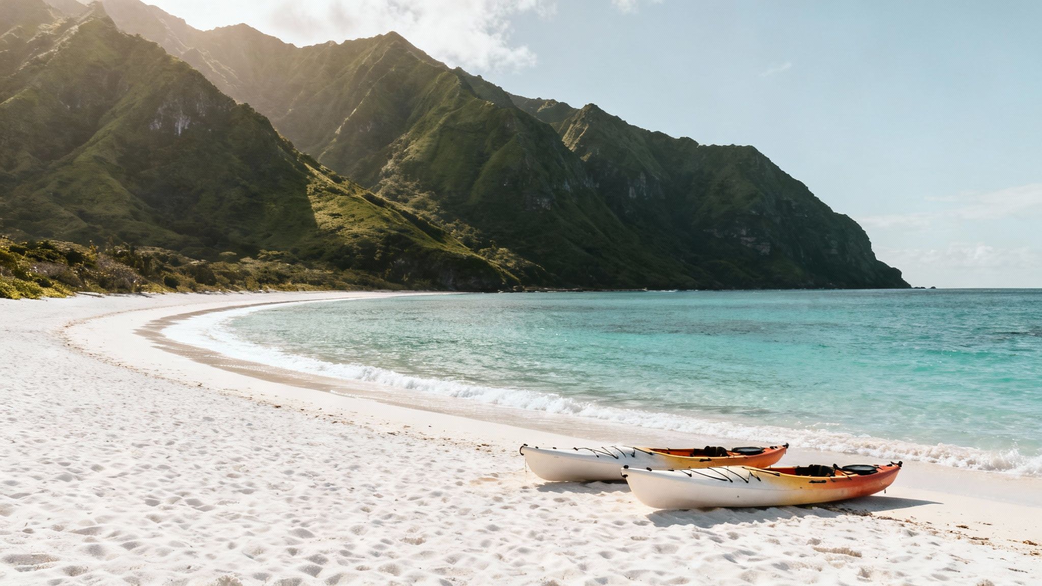 Two kayaks rest on a stunning white sand tropical beach with turquoise water and lush green mountains.