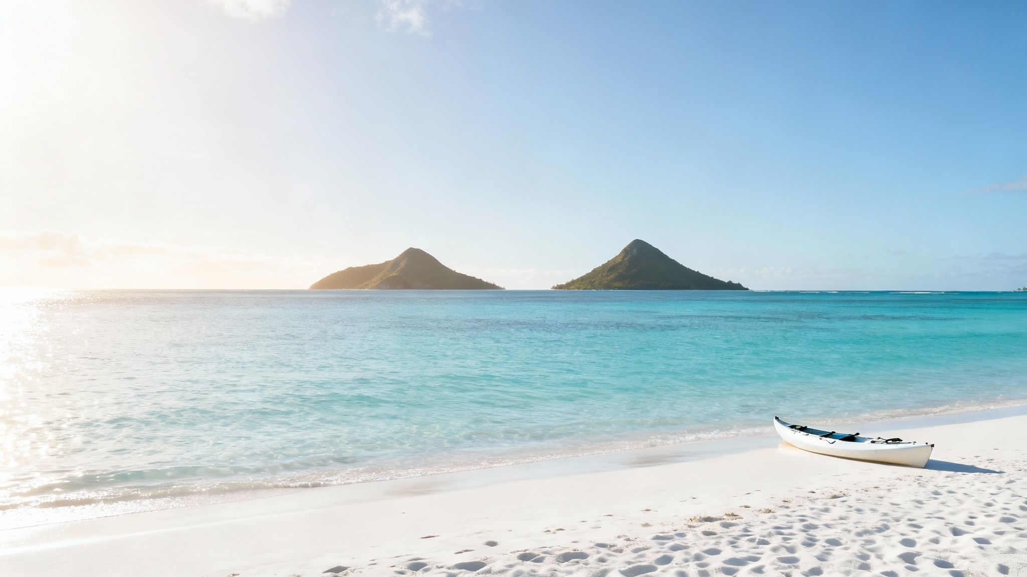 Beautiful Hawaiian beach with a white kayak, clear turquoise water, and two green islands.