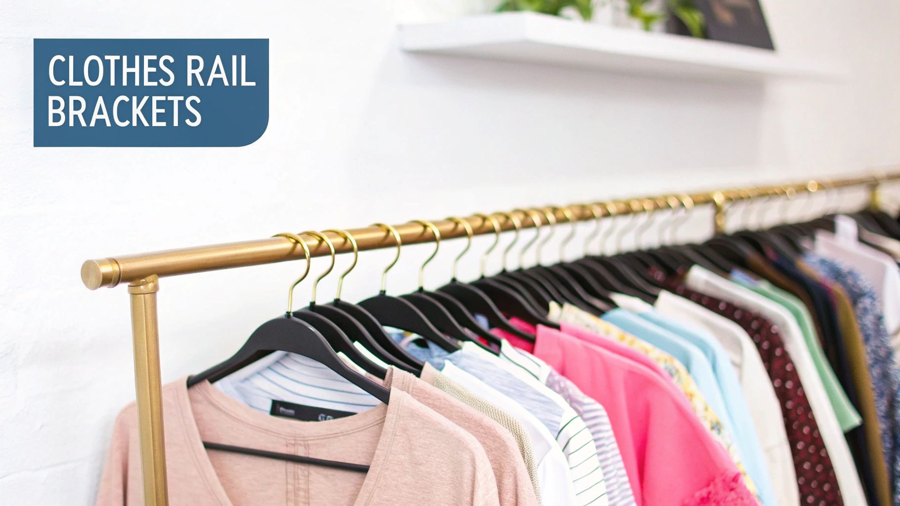 A long gold clothes rail filled with various colored clothes on black hangers, set against a white wall.