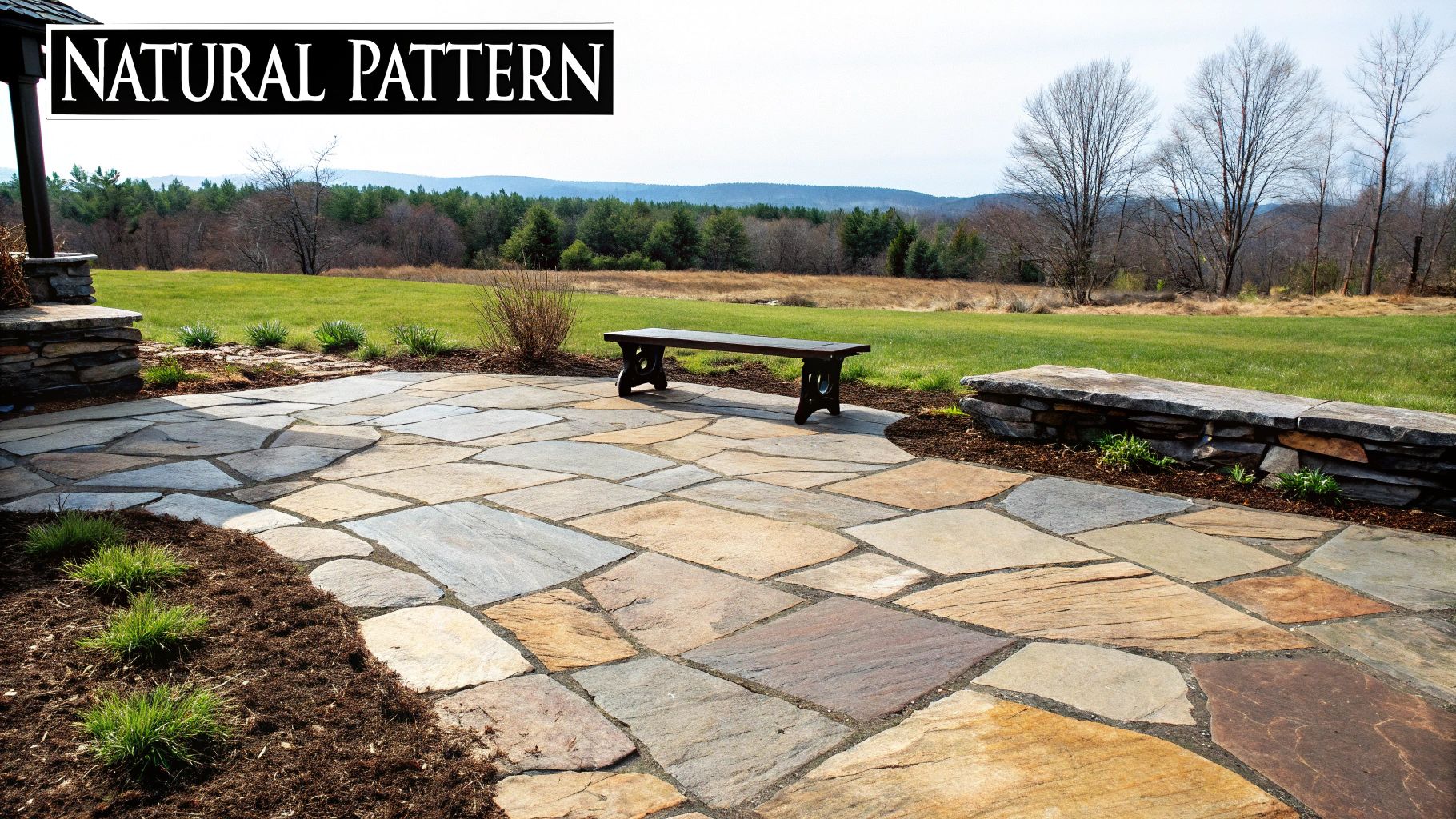 A natural stone patio with a wooden bench, stone wall, and scenic outdoor landscape.