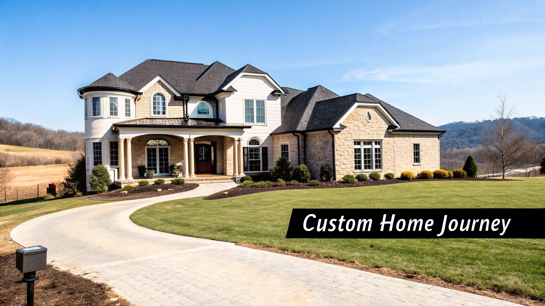 A beautiful custom luxury house with a paved driveway, green lawn, and distant hills under a clear sky.