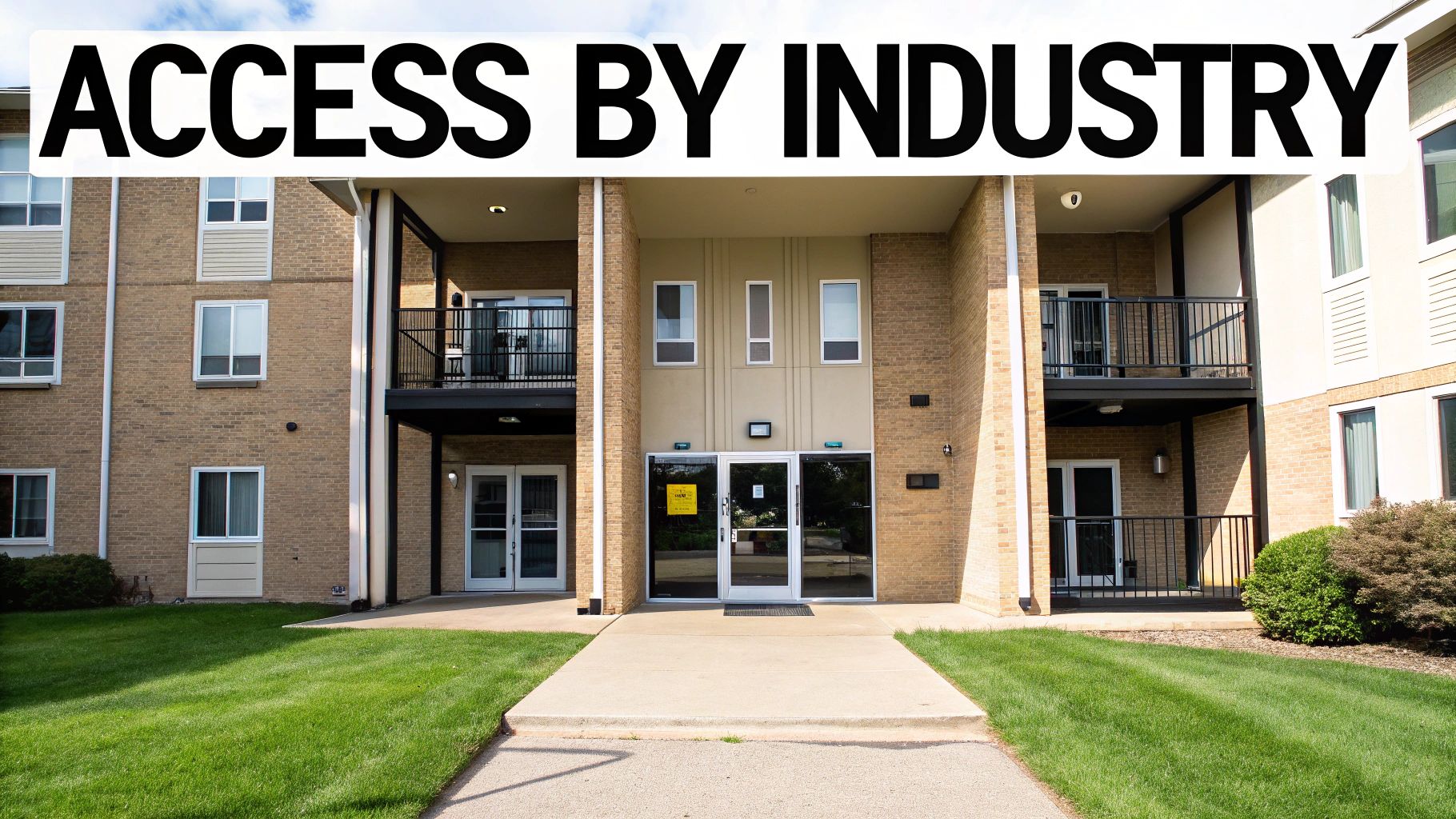 A person in a business suit holding a key fob near a door reader in a modern office hallway