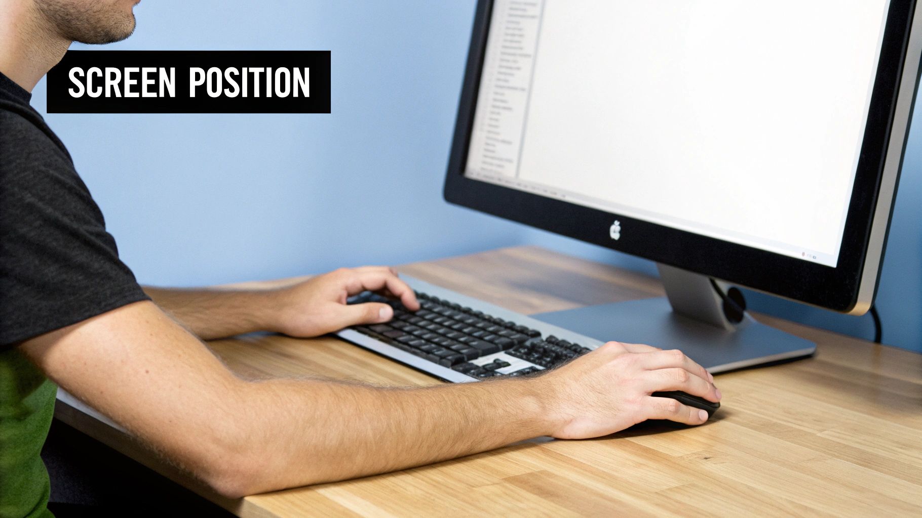 A person uses a computer at a desk, showing proper screen position for ergonomics.