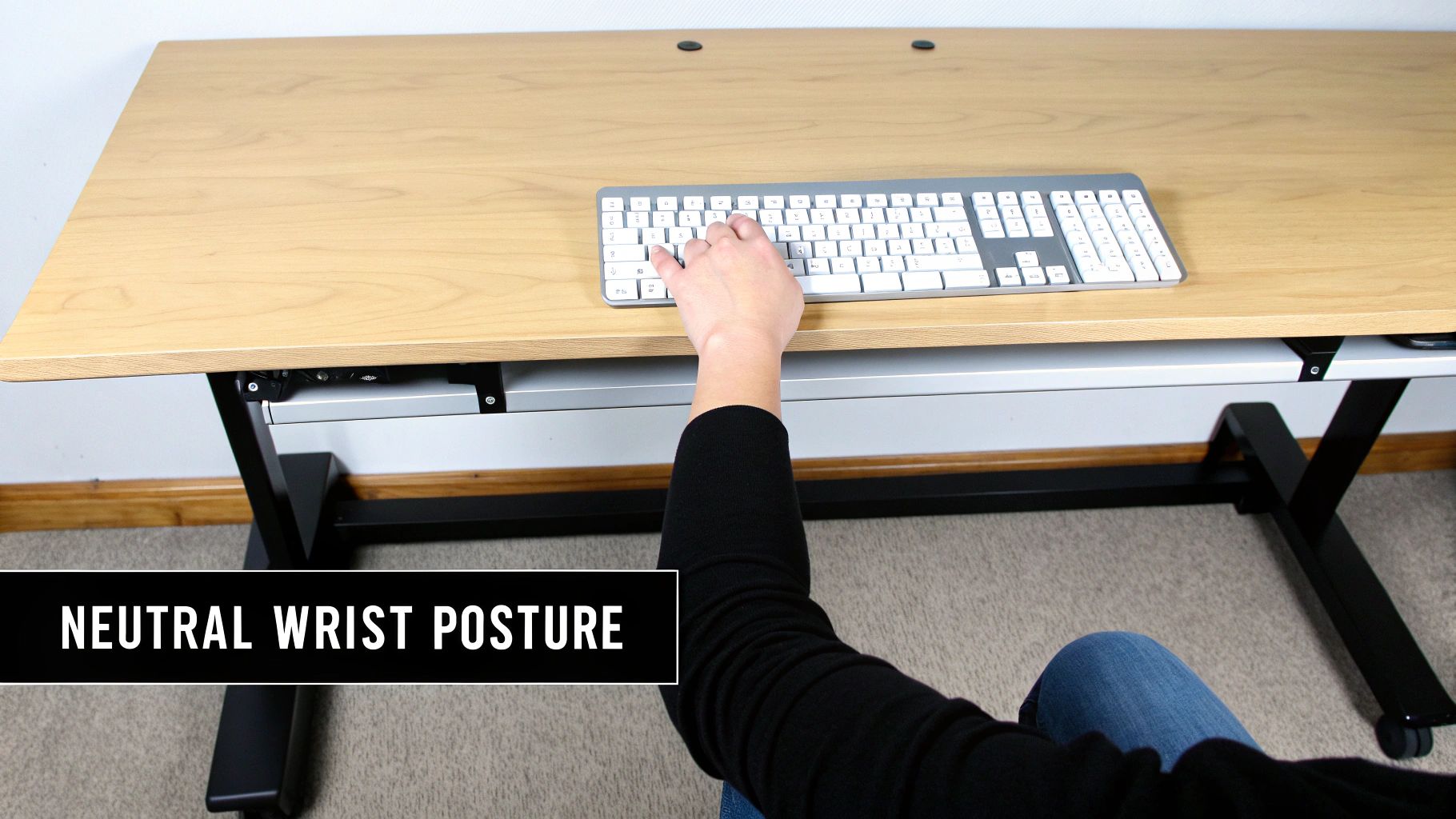 Close-up of a person's hands typing on a keyboard, demonstrating neutral wrist posture on a wooden desk.