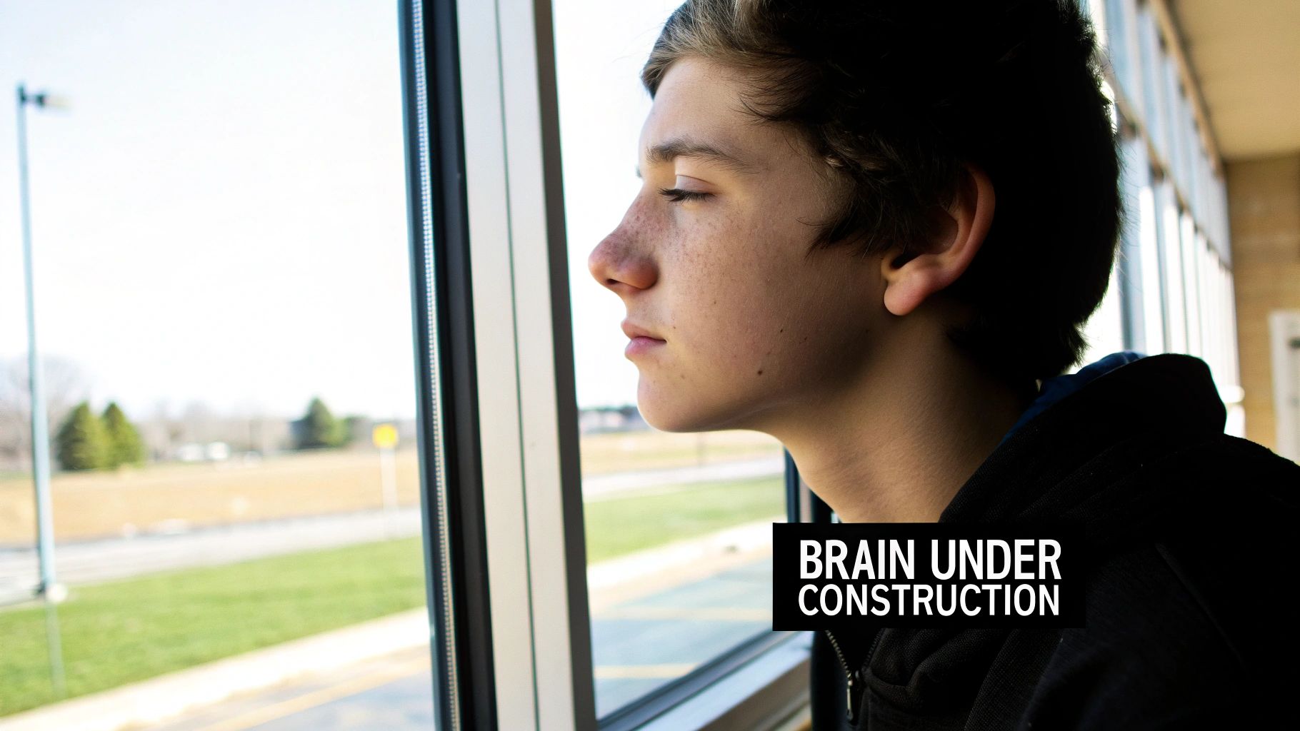 A young person with eyes closed looks thoughtfully out a window, with 'Brain Under Construction' text.
