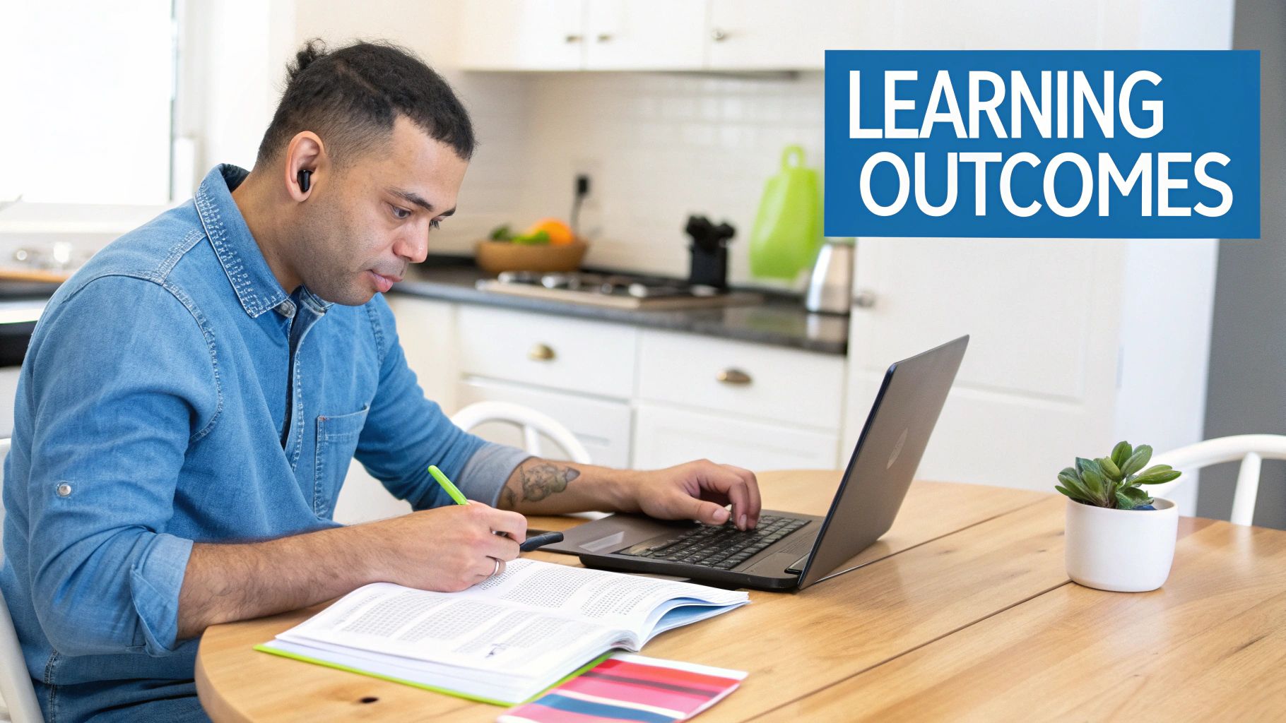 A man in a denim shirt studies at a wooden table, writing in a book and typing on a laptop, with a "Learning Outcomes" sign in the background.