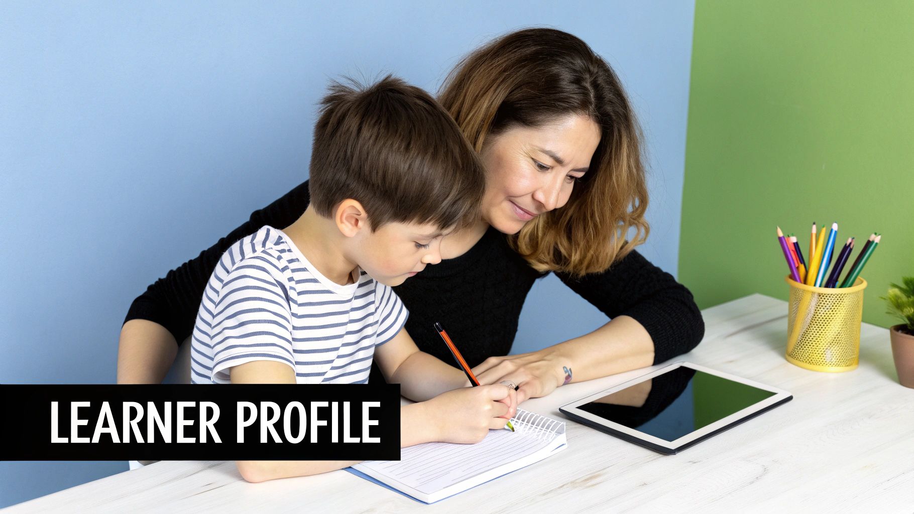 Smiling woman assists a young child writing in a notebook at a desk with school supplies.