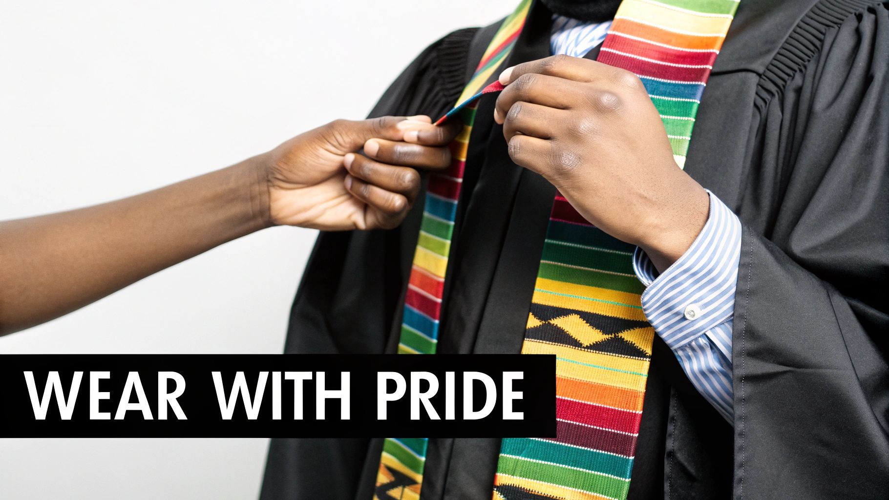 Two hands adjust a vibrant kente stole on a person wearing a black graduation gown, with text “WEAR WITH PRIDE”.