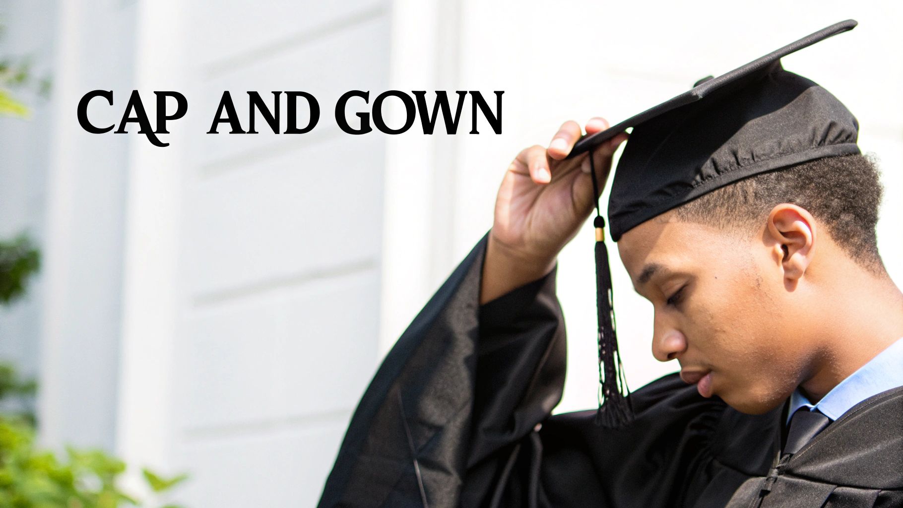 A young person adjusting a black graduation cap with a tassel while wearing a gown.