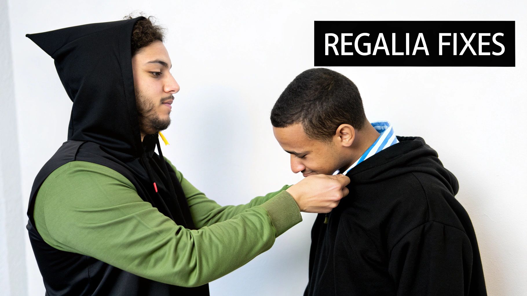 A man in a green-sleeved hoodie adjusts the collar of another man's black hoodie.
