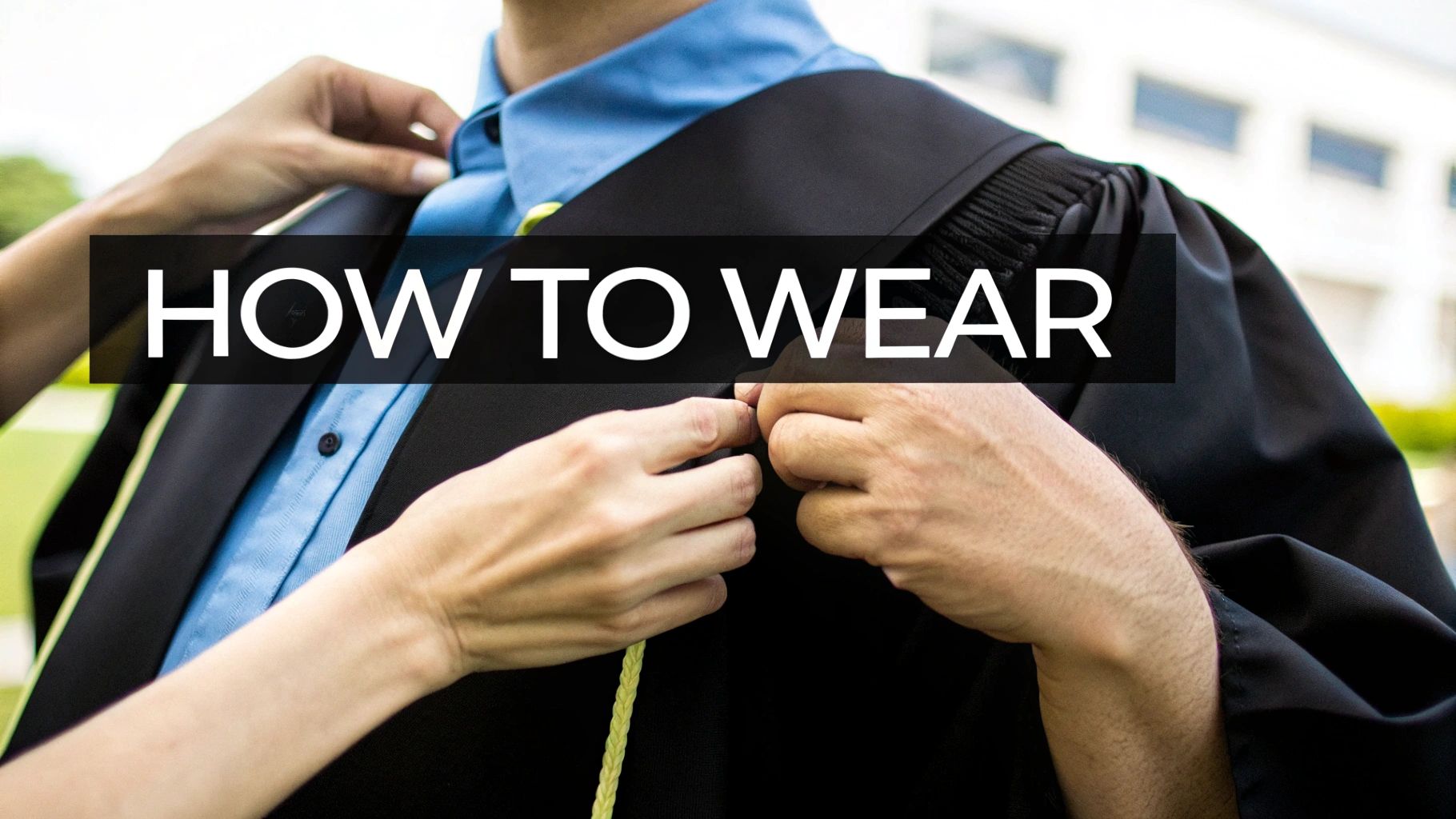 Hands adjusting a black graduation gown worn over a light blue shirt, with a yellow honor cord.