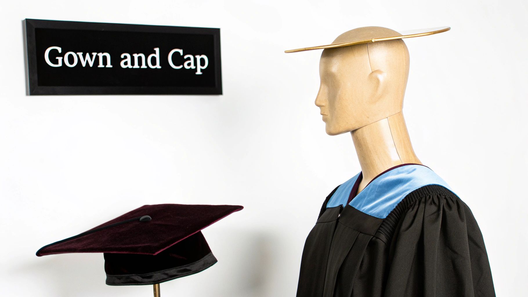 A student in a black master's gown and cap smiles while holding a diploma.