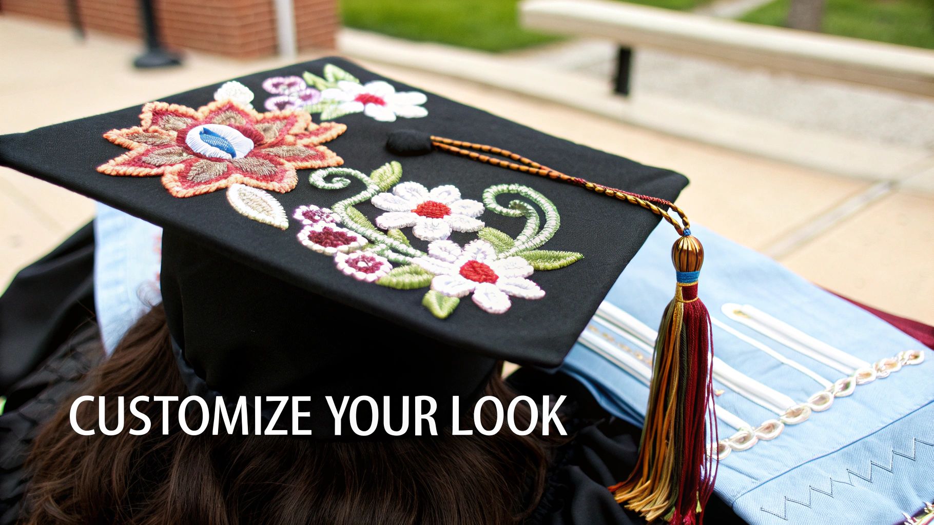 A graduate wears a black graduation cap adorned with colorful embroidered flowers and a multi-colored tassel.
