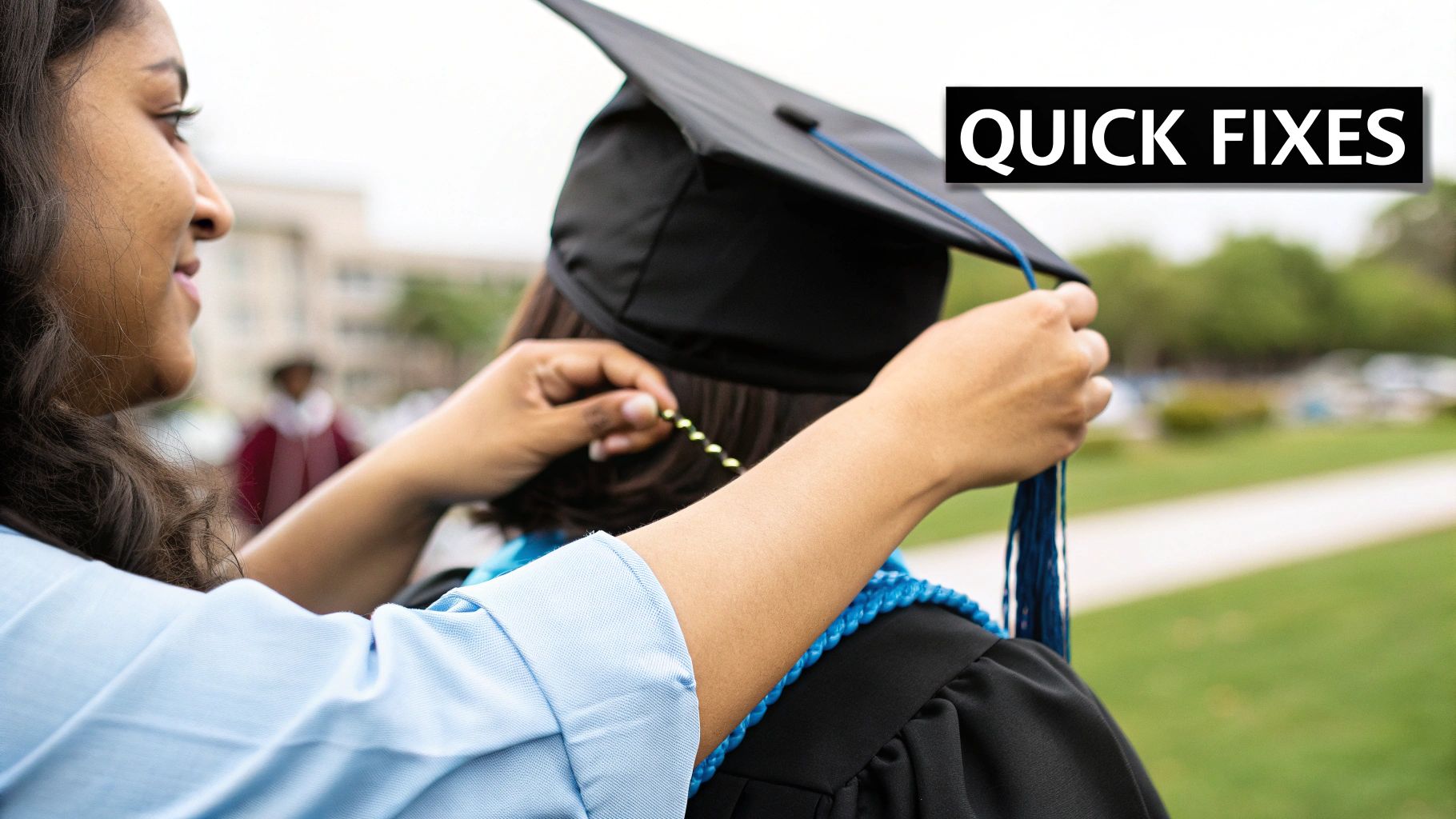 A student helps another graduate adjust their cap and academic regalia on graduation day.