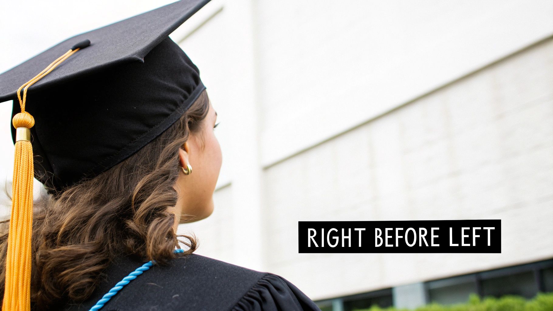 A graduate from behind, wearing a black cap and gown with a gold tassel, looking ahead.