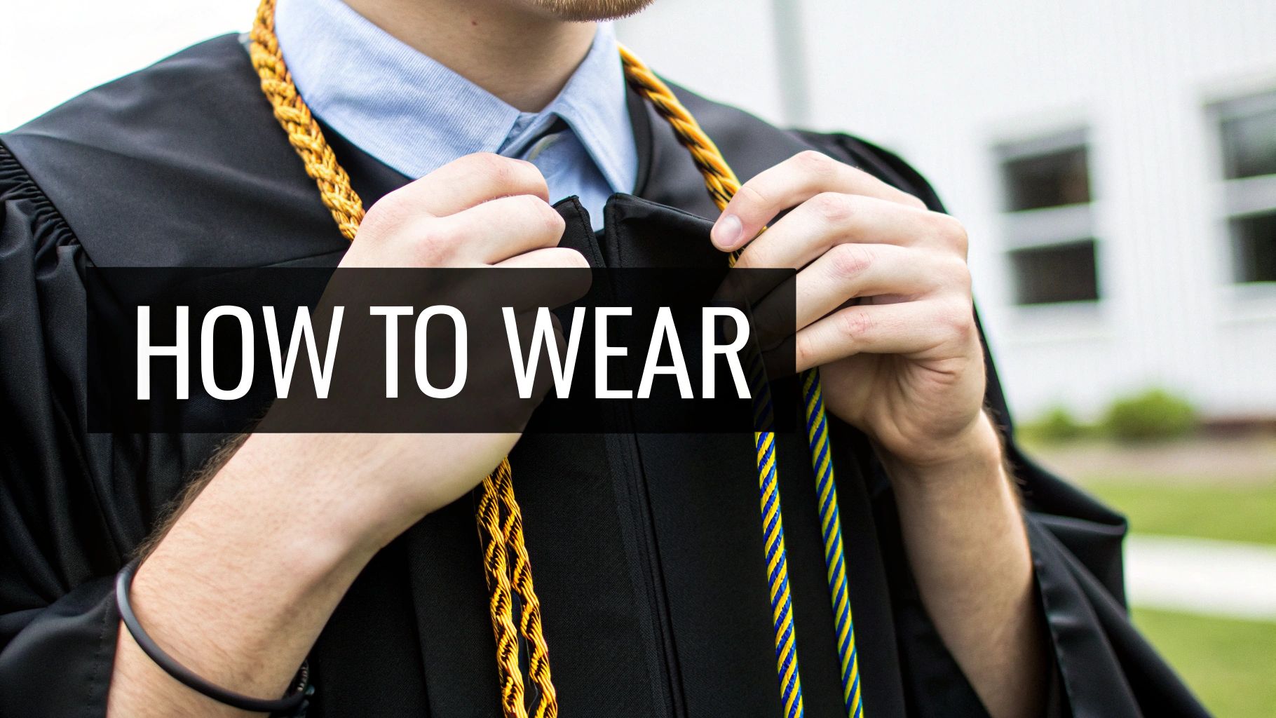 Hands of a graduate adjusting gold and blue/yellow honor cords over a black gown and blue shirt.