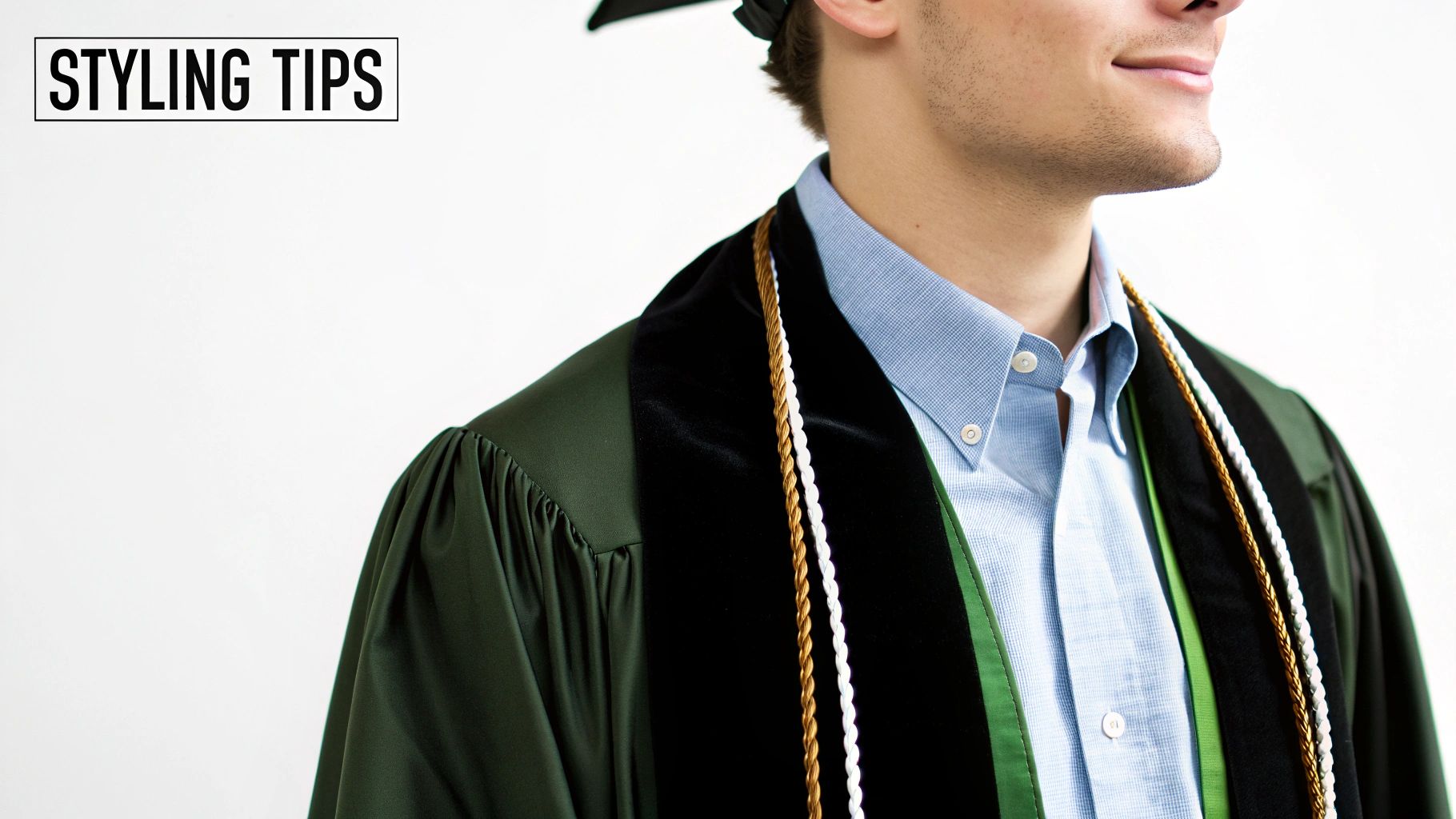 Close-up of a person in a dark green graduation gown, black velvet stole, and light blue shirt.