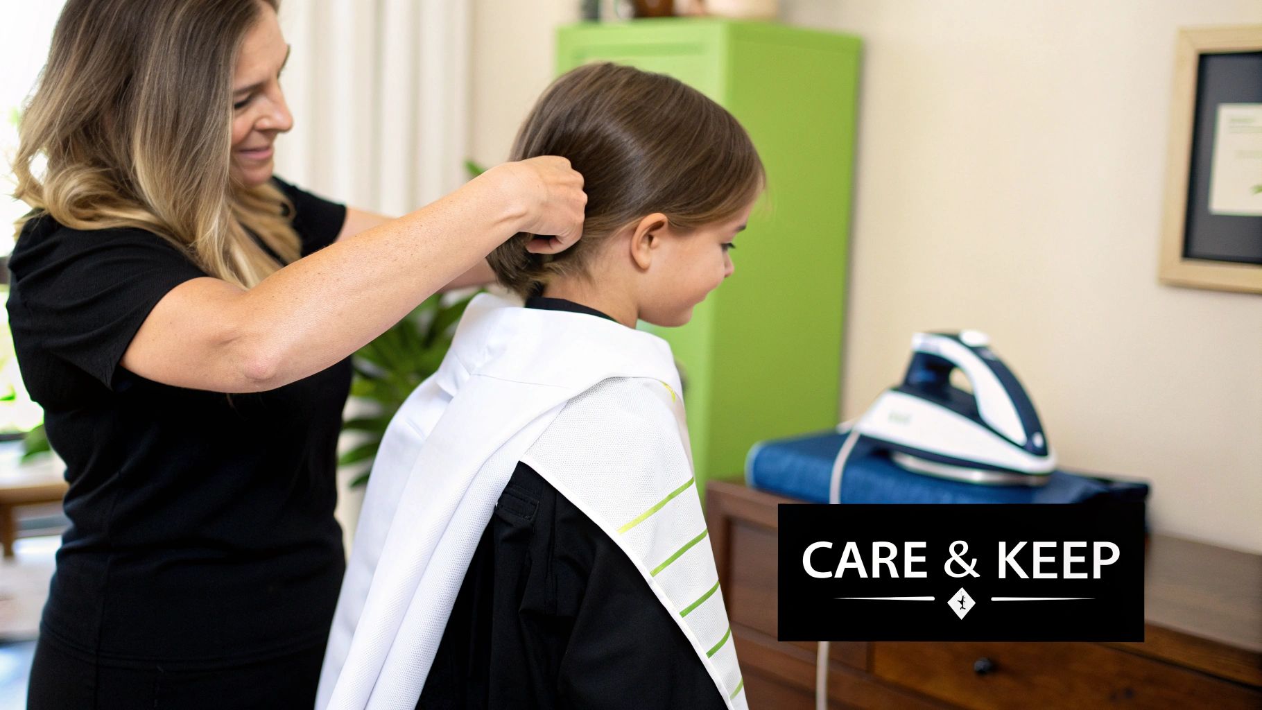 An adult carefully helps a young child style their hair, who is wearing a white graduation stole with green stripes.