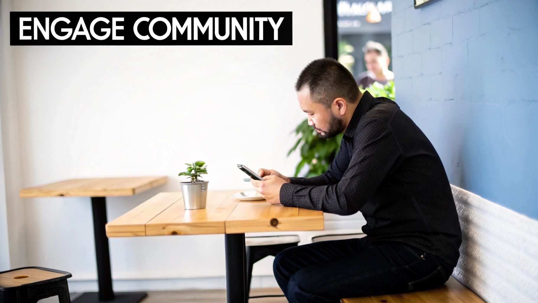 A man looking at his smartphone at a wooden cafe table, with 'ENGAGE COMMUNITY' text.