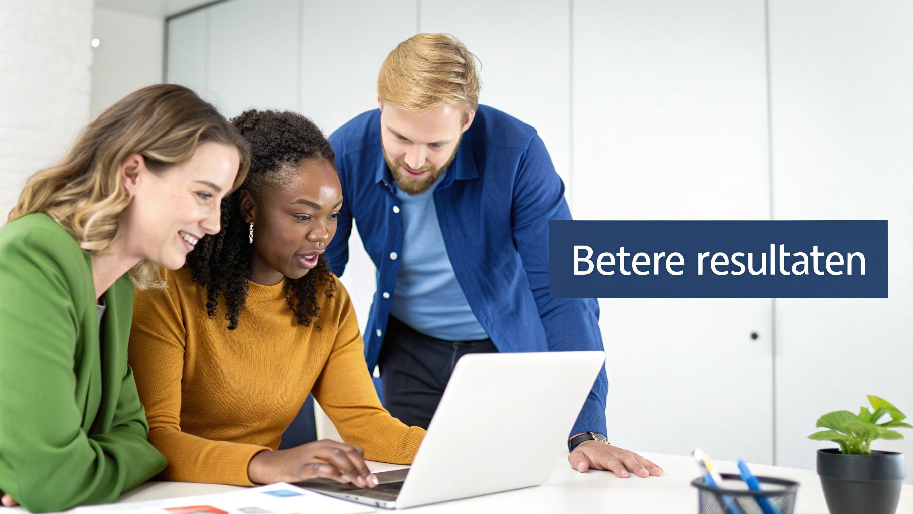 Drie diverse teamleden werken samen aan laptop en bespreken betere resultaten in moderne kantooromgeving