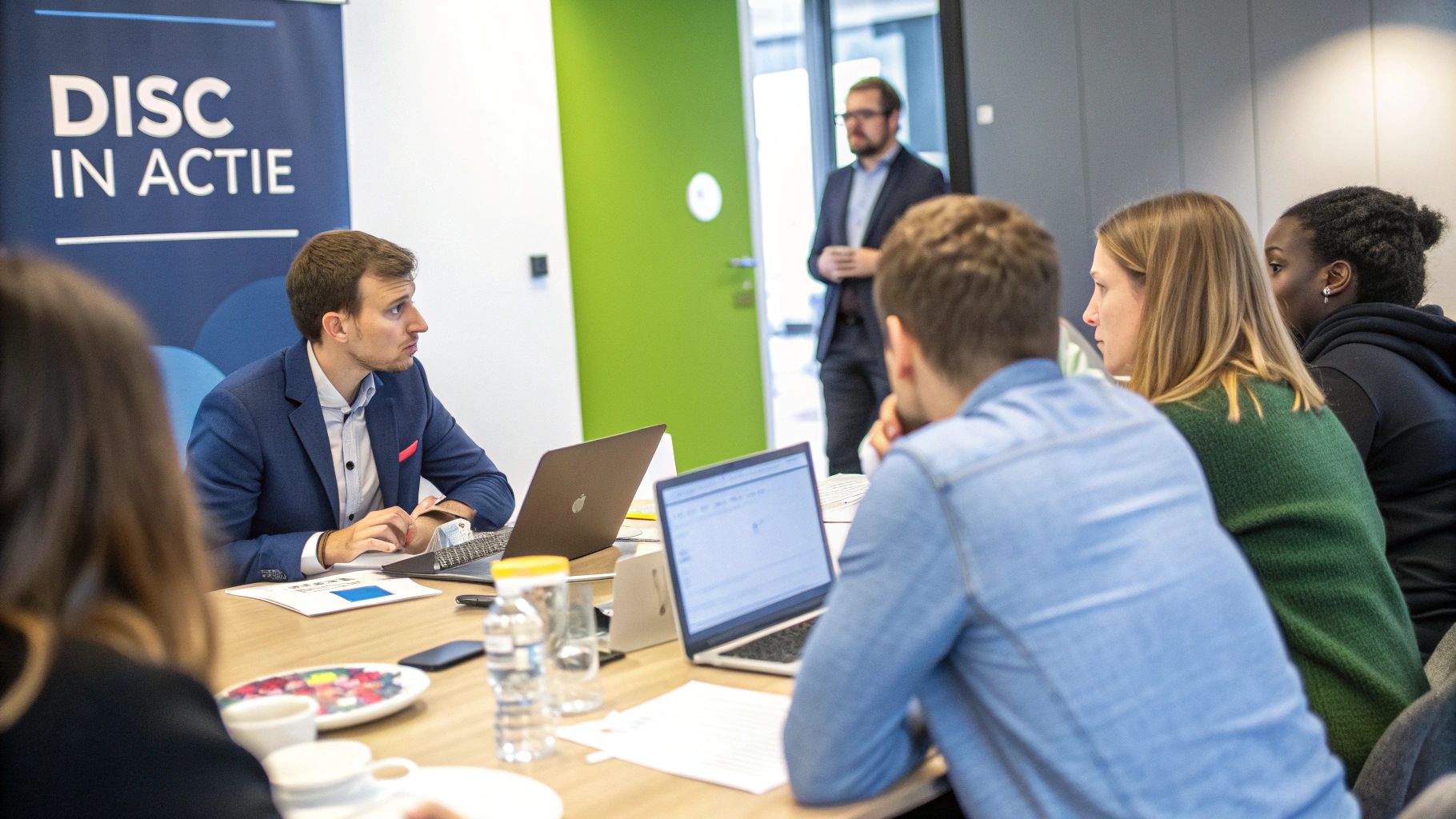 Een team dat samenwerkt en communiceert in een moderne kantooromgeving, wat de praktijktoepassing van DISC illustreert.