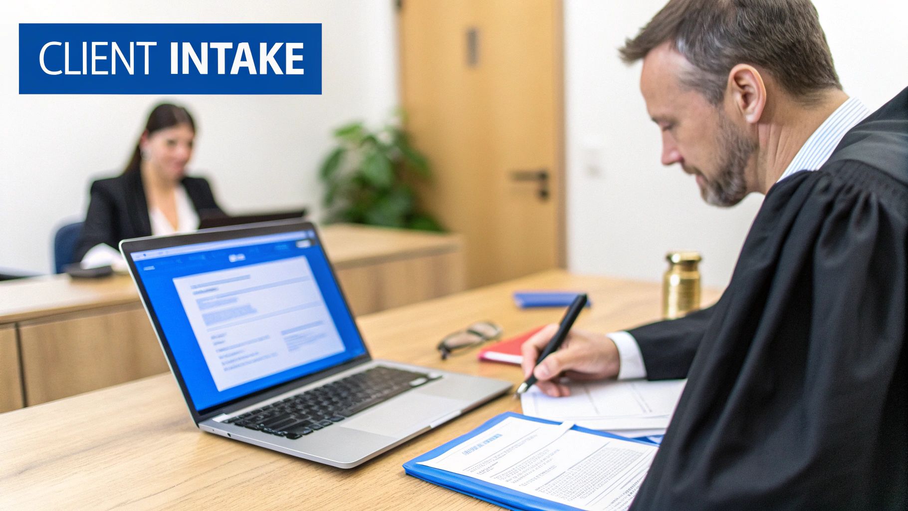 A male lawyer in a robe writes on documents during a client intake session.