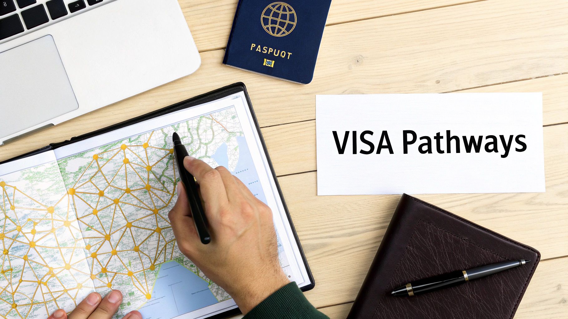 A person pointing at a map with a network of routes, next to a laptop, passport, and a 'VISA Pathways' card.
