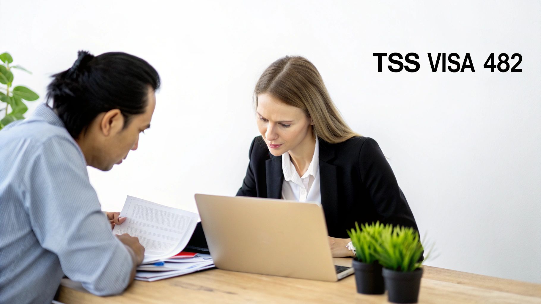 A man and a woman reviewing documents and a laptop, related to TSS VISA 482.